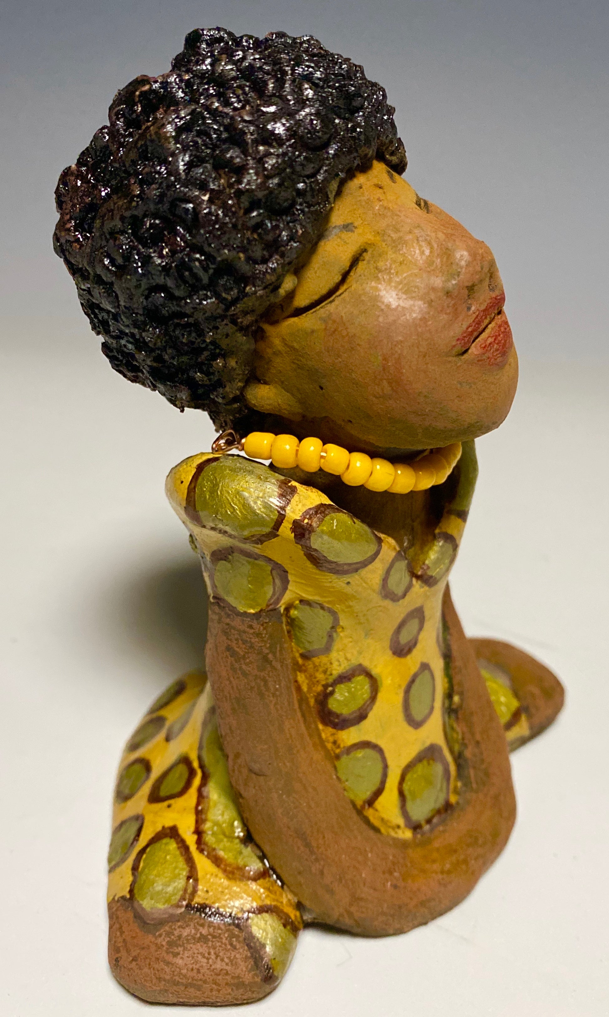 Meet Shelia! Shelia stands" 5 x 4" x 3" and weighs 11 ozs. She wears a cute spotted autumn yellow dress with matching beads. She has a lovely honey brown complexion with an awesome black afro.. Her long loving arms rest at her side. With the current situation we All are going through, Shelia will place a smile on your face during this challenging time. 