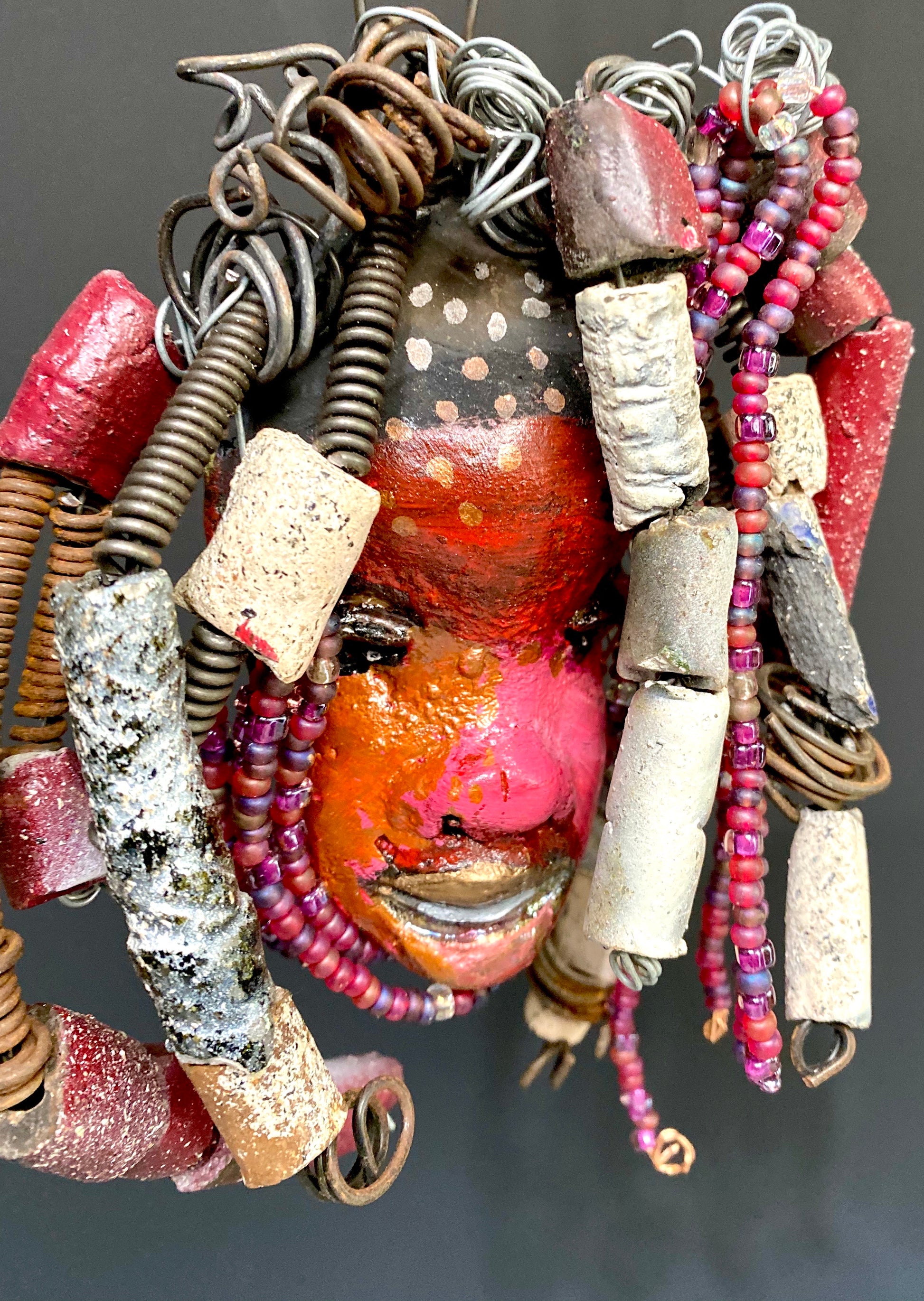 I started making mask soon after seeing authentic African artwork at the Smithsonian Museum of African Art. I was in total awe. I was inspired by my visit there..  Kylie has a multi colored red tone  metallic copper complexion. She is 7" x 5" and weighs 8 ozs. Kylie has  over 50 mini beads and handmade raku beads. Kylie has over 4 feet of 16 gauge wire hair.