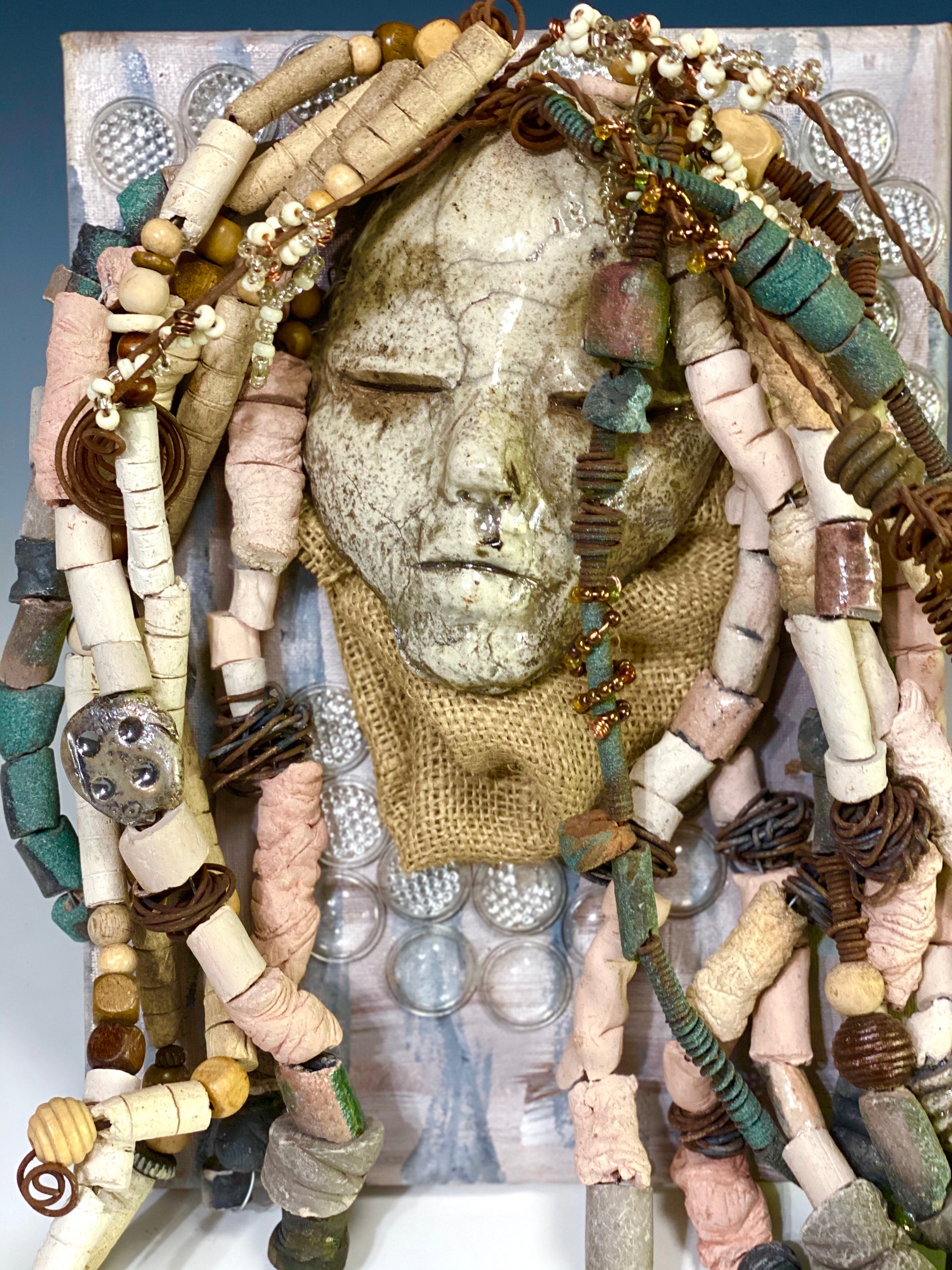 Alaskaya is mounted on a 9"x 12" painted canvas. I spent about 4 hours or more just fixing Alaskaya's hair and attaching her beads! She has over 50 feet of 16 gauge wire and copper strands for hair and over 50 raku beads. Alaskaya weighs 4.03 lbs. Alaskaya has a white crackle face with an angelic demeanor. Alaskaya is ready to be hung!