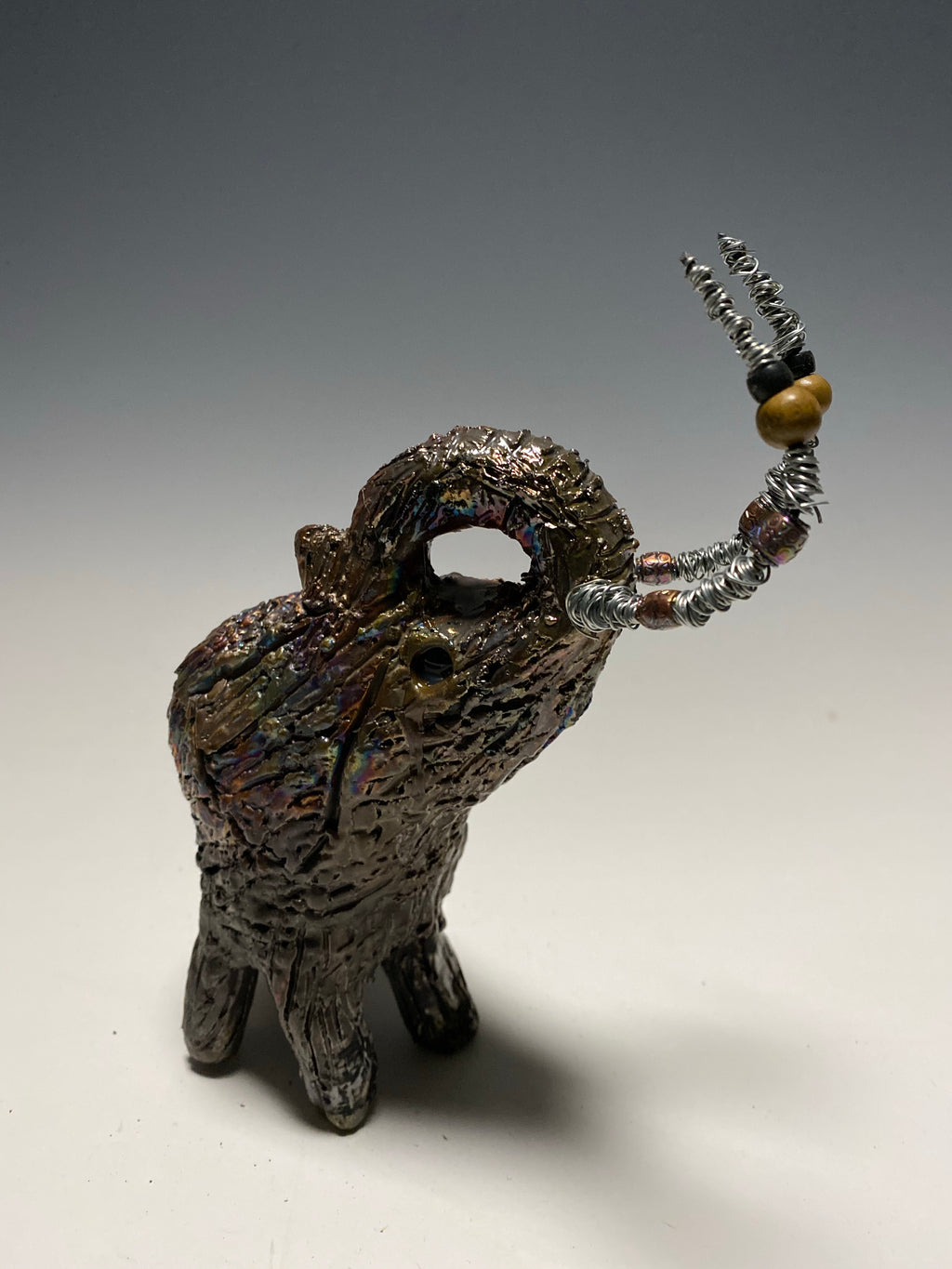 Raku Elephant Have you HERD!!!!!!  Just one of these lovely Raku Fired Elephant will make an excellent gift for your  friend, sorority or for your home’ special place centerpiece.  6" x 4" x 4" 1lbs Wood beaded with  silver tusk Beautiful metallic raku colors For decorative purposely only.