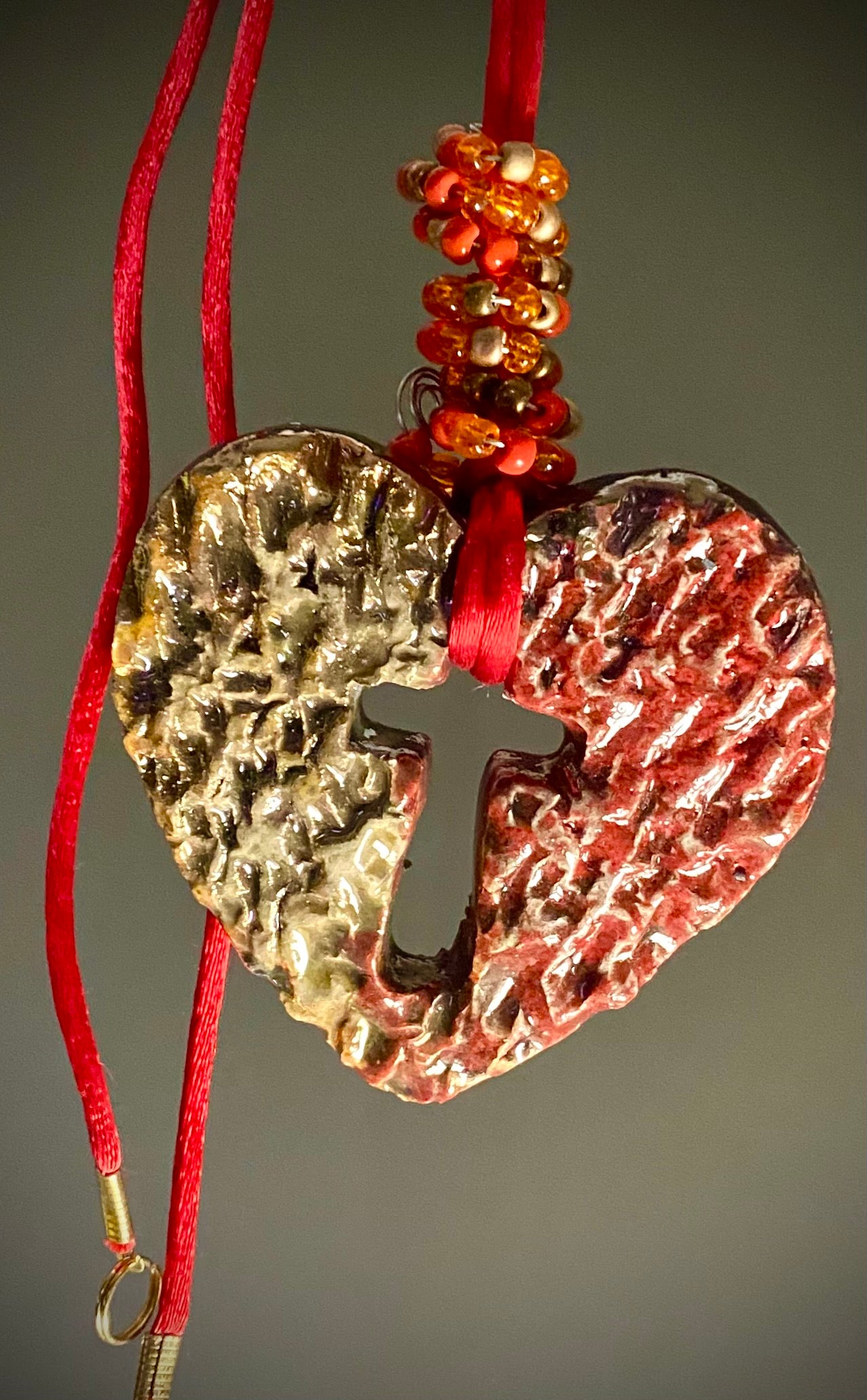Have A Heart ! Each heart pendant is handmade with love! It is 3"x 3" and weighs approx. 3ozs. This pendant has a copper gold metallic raku glazes that renders a unique translucent  patina. The heart has a textured pattern . It holds a spiral of red mini beads on a spiral copper wire. This pendant has a nice 12" red suede cord!