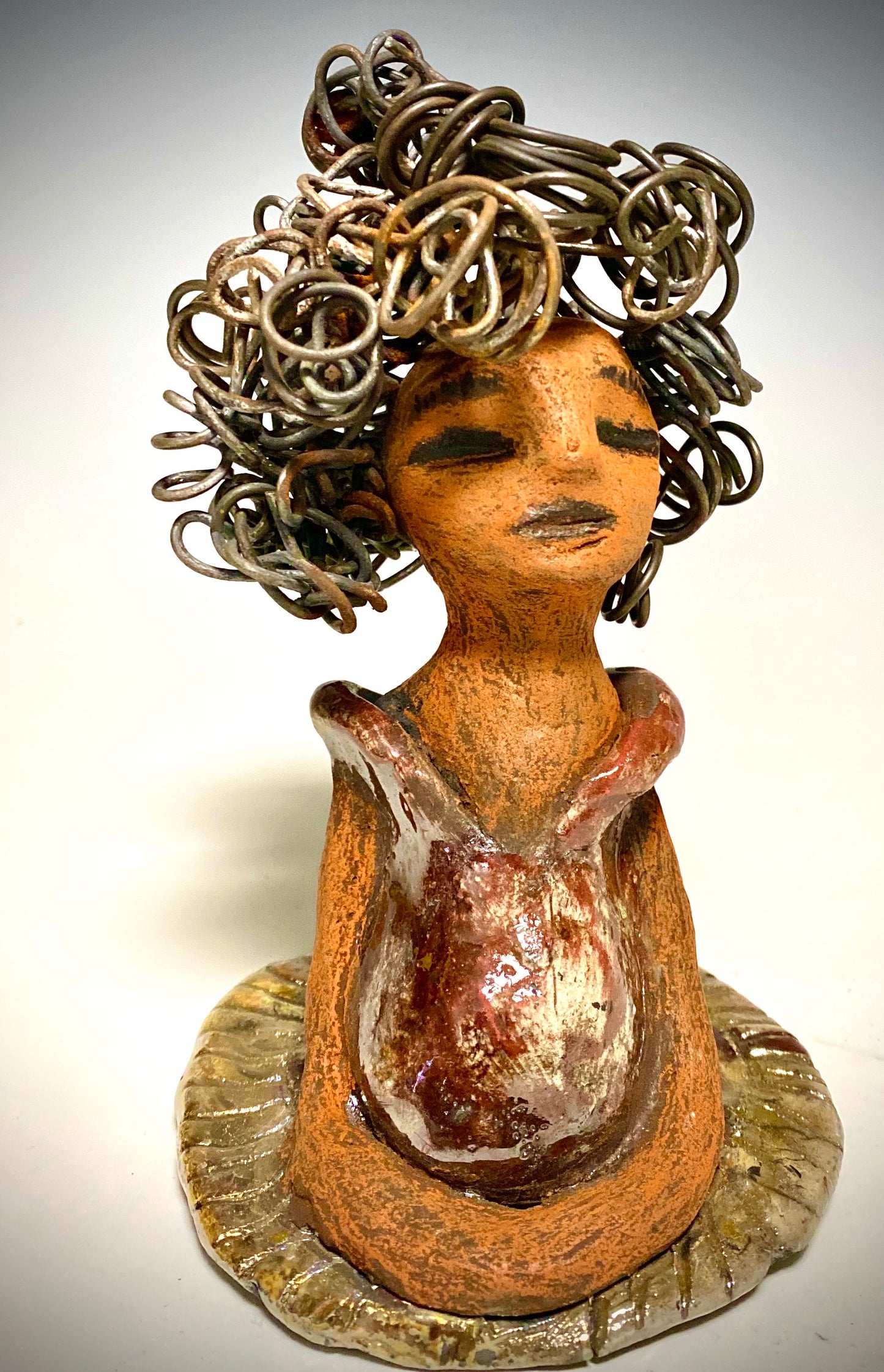 Meet Carleen! Carleen  stands 6" x 4" x 4" and weighs 12 ozs. Carleen has a honey brown complexion with 16 gauge curled wire hair. She wears an copper metallic dress. Carleen  has her long loving arms at her side as she rest and waits.