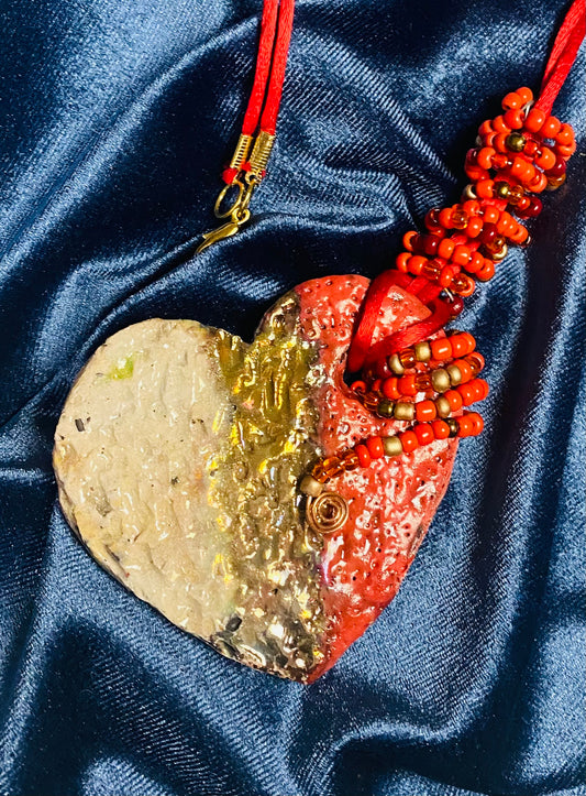 Have A Heart ! Each heart pendant is handmade with love! It is 3"x 3" and weighs approx. 3ozs. This pendant has a copper gold metallic raku glazes that renders a unique translucent  patina. The heart has a textured pattern . It holds a spiral of red mini beads on a spiral copper wire. This pendant has a nice 12" red suede cord!