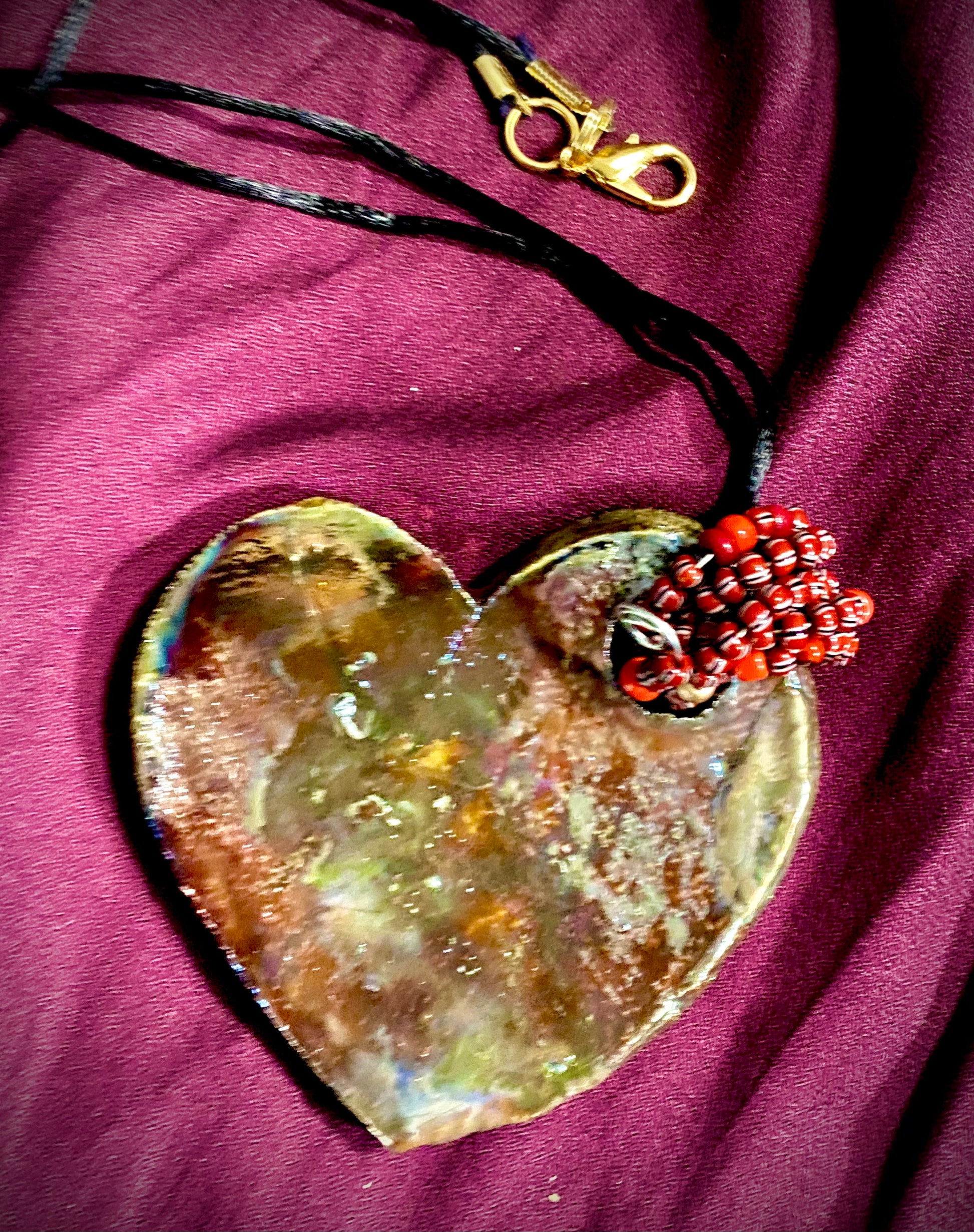  Have A Heart ! Each heart pendant is handmade with love! It is 3"x 3" and weighs approx. 3ozs. This pendant has a colorful copper metallic raku glazes that renders a unique translucent patina. The heart has a textured pattern . Both sides are  are different and equally beautiful! It holds a spiral of blue mini beads on a spiral copper wire. This pendant has a nice 12" black rattail  cord!