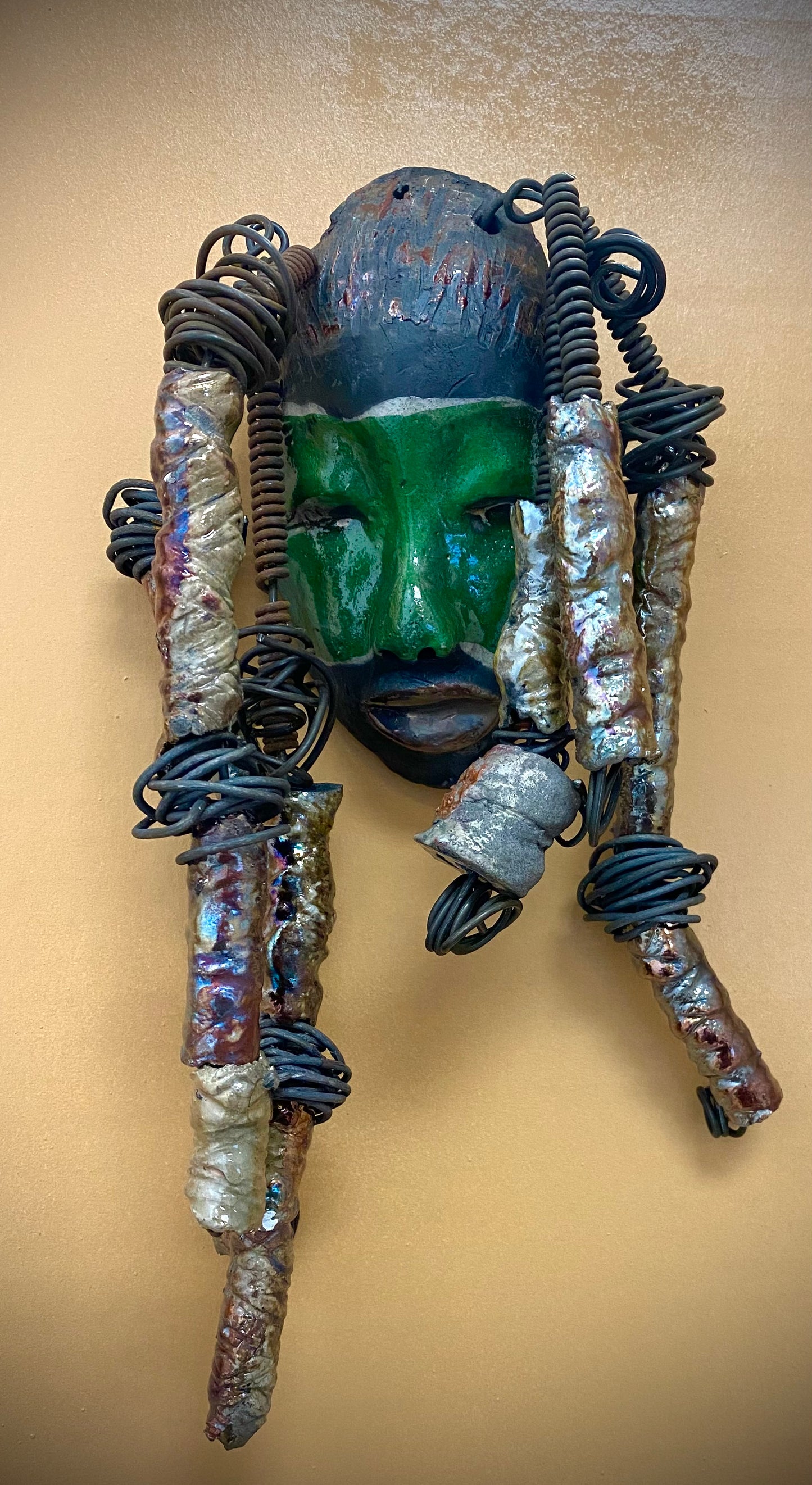 Meet Craig! I am going to make more with colors in the face like Craig. I like how the green and copper complements each other.  I started making art soon after seeing authentic African artwork at the Smithsonian Museum of African Art. I was in total awe. Craig was inspired by my visit there.  Craig is   4"x 10" and weighs 12 ozs. He has a two tone  green and copper face. Craig has hand coiled 16 gauge wire  hair with over  10 metallic raku beads.