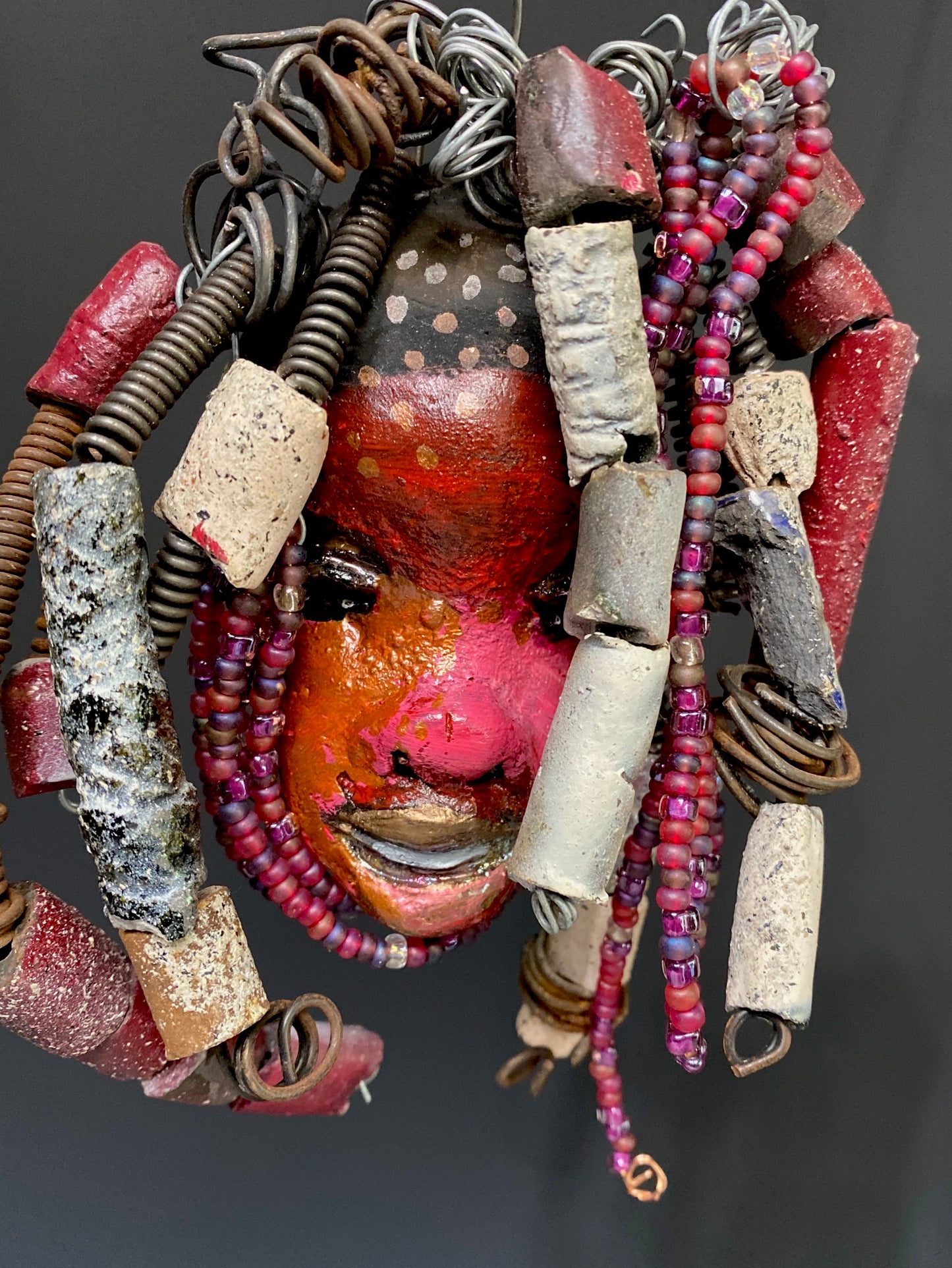 I started making mask soon after seeing authentic African artwork at the Smithsonian Museum of African Art. I was in total awe. I was inspired by my visit there..  Kylie has a multi colored red tone  metallic copper complexion. She is 7" x 5" and weighs 8 ozs. Kylie has  over 50 mini beads and handmade raku beads. Kylie has over 4 feet of 16 gauge wire hair.