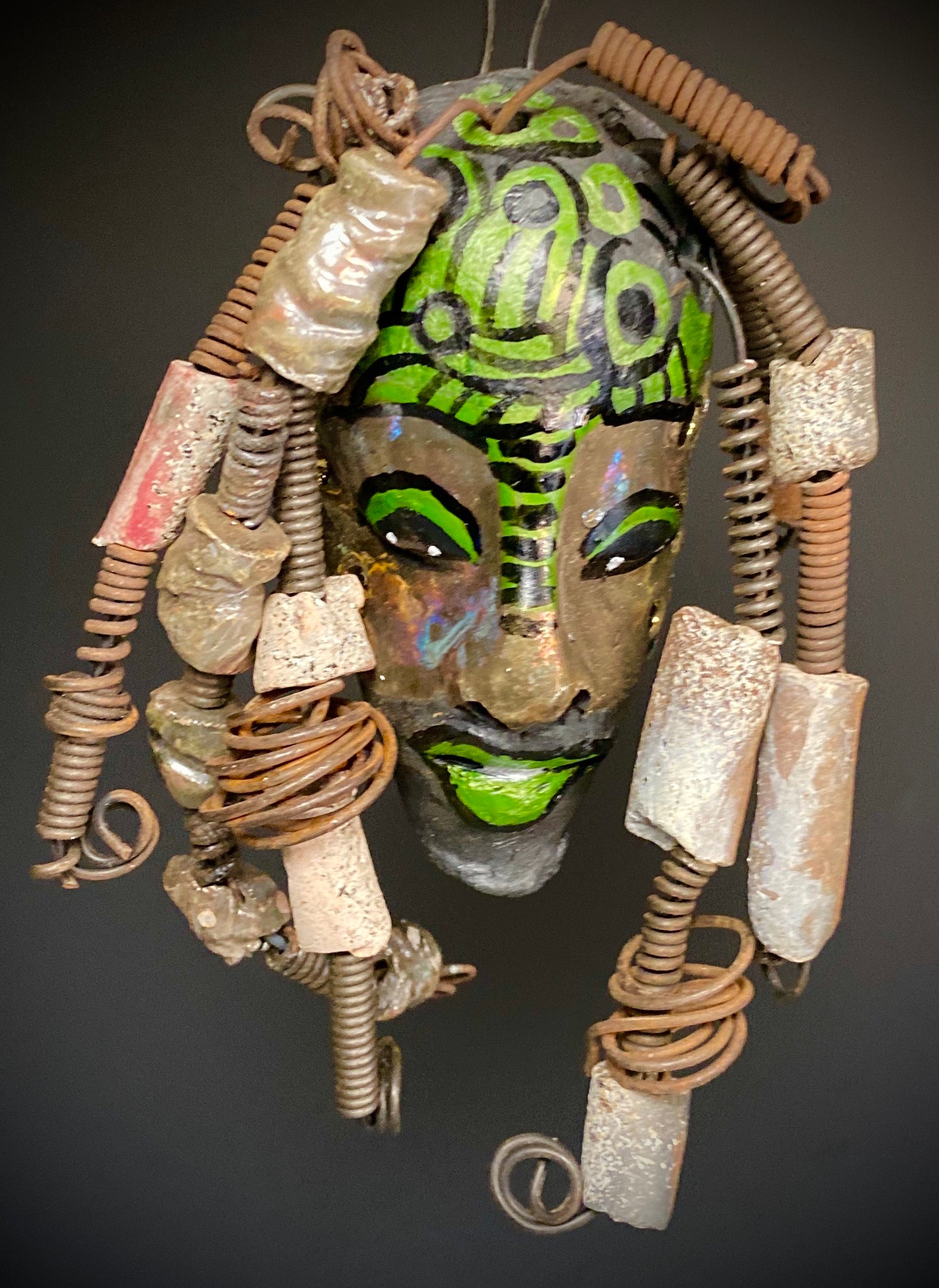 I started making art soon after seeing authentic African artwork at the Smithsonian Museum of African Art. I was in total awe. This work was inspired by my visit there.  Meet the Green Man! The Green Man is   5"x 6". He has green and black horizontal stripes with bright eyes and green lips. He has hand coiled 16 gauge wire  hair with over  10 raku beads.