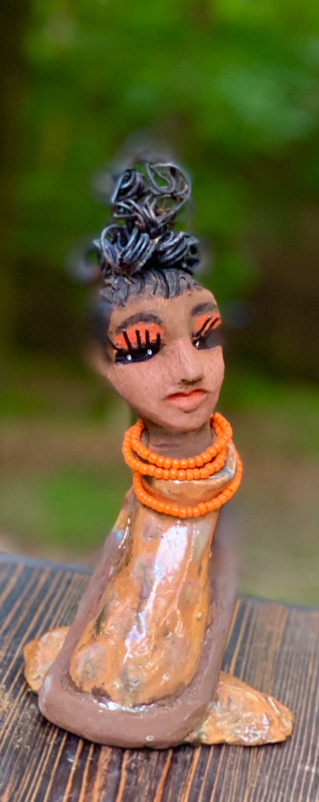 Meet Abimbola ! Abimbola stands 7' x 4"x 2" and weighs 1.3 lb. She has bright eyes and a nice honey brown complexion Abimbola  has over 5 feet of 16 gauge wire hair wrapped in a bun. Her long trademark arms rest at her side. Abimbola dress is a loving glossy orange mix with copper flashes. Abimbola is waiting for you to invite her into your home! 