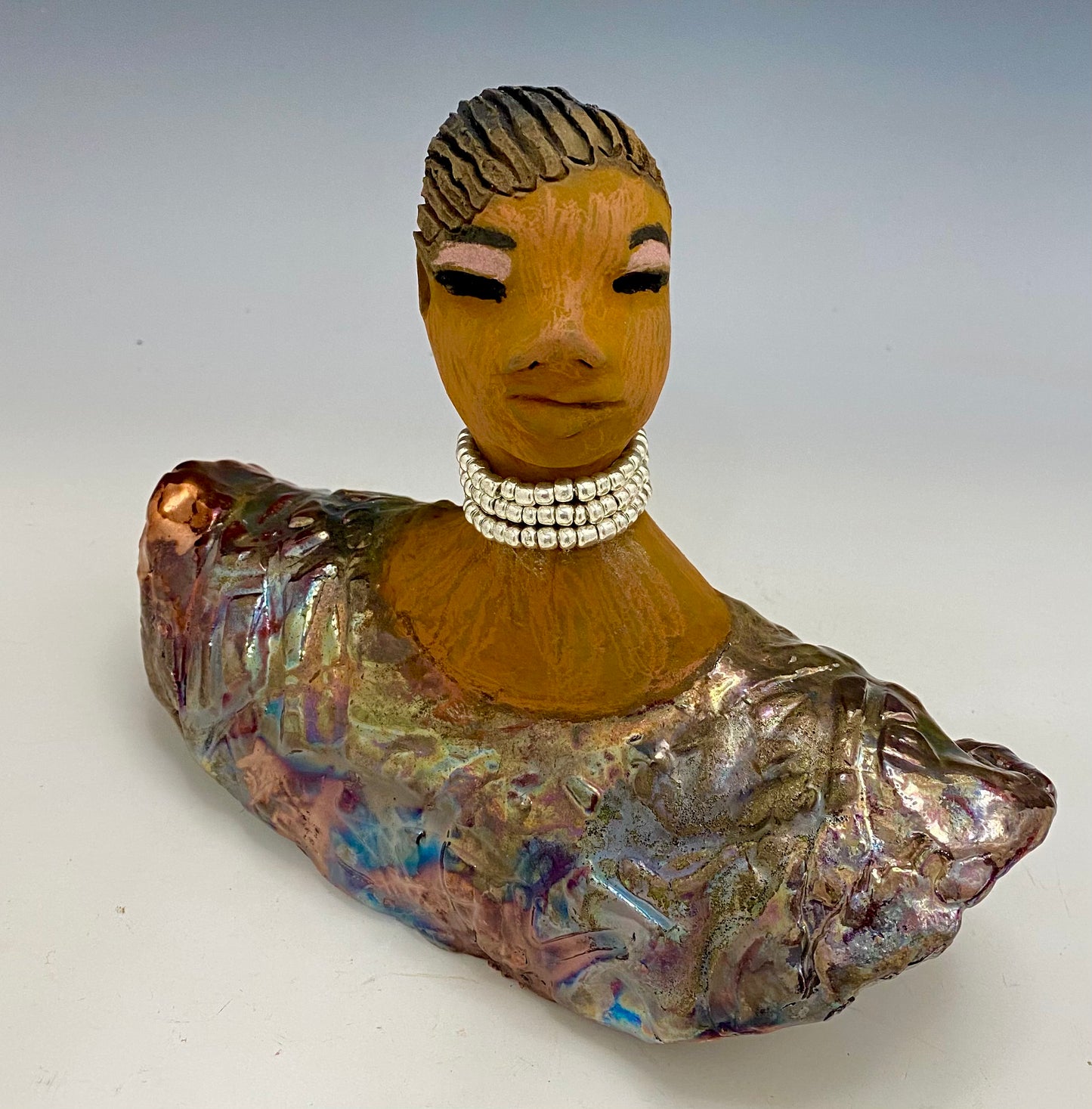 Belinda looks up with joy and anticipation! Belinda stands 6" x 8" x 4" and weighs 1.40 lbs. She has a beautiful textured copper robe trim. Belinda has braided clay hair. She has a honey brown complexion and soft light brown lips. Belinda will make for great conversation in your home.