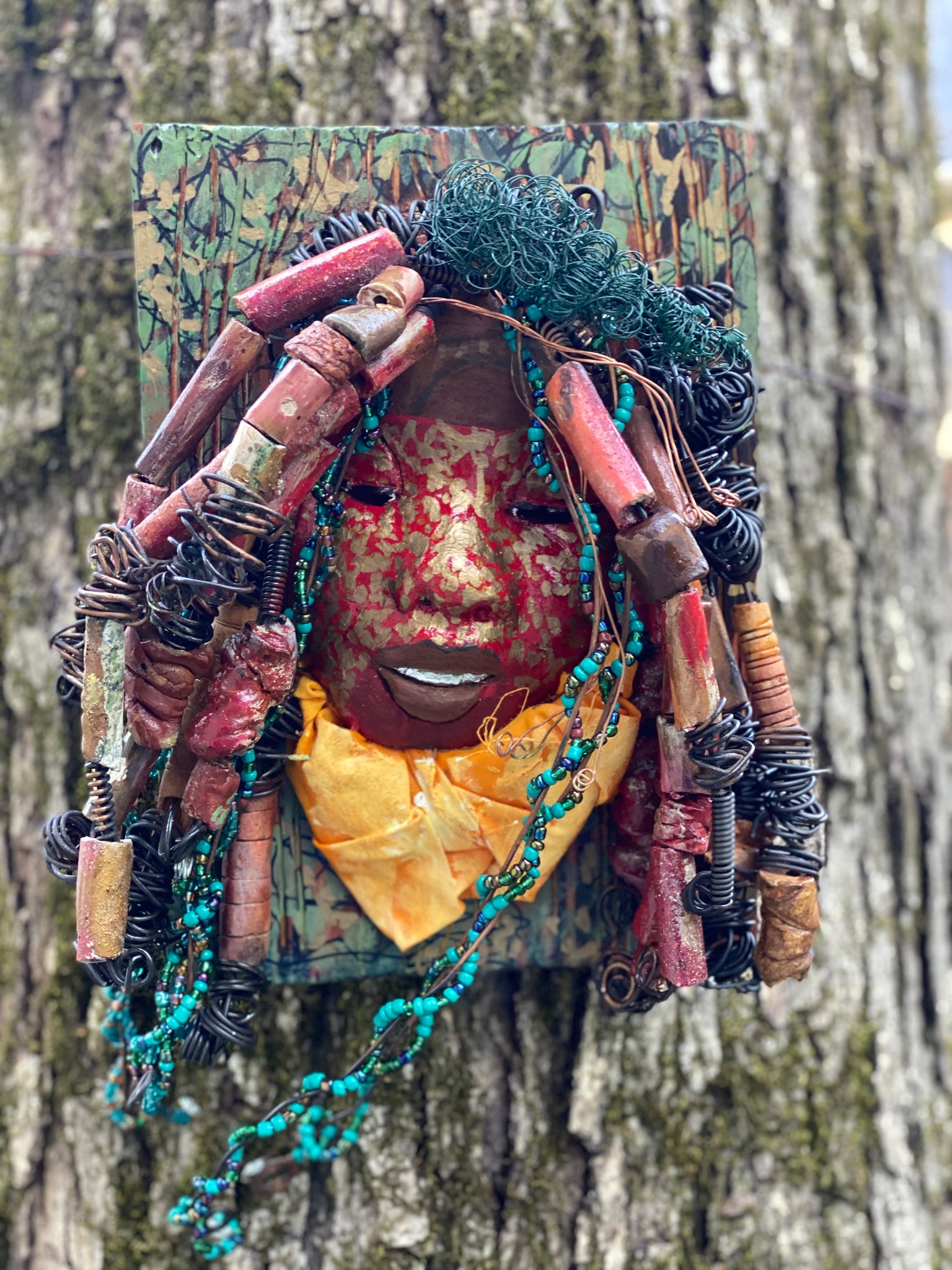 Deandra is one of a new 2022  series of tribal masks that are mounted on wood. I started making art soon after seeing authentic African artwork at the Smithsonian Museum of African Art. I was in total awe. Deandra is 7” x 10 x 1 and weighs 3.7 lbs.  She has a contagious smile. 25 handmade raku fired beads Over 60 mini 6mm multi colored beads  Over 60 feet of 16 and 24 gauge twisted wire for hair!