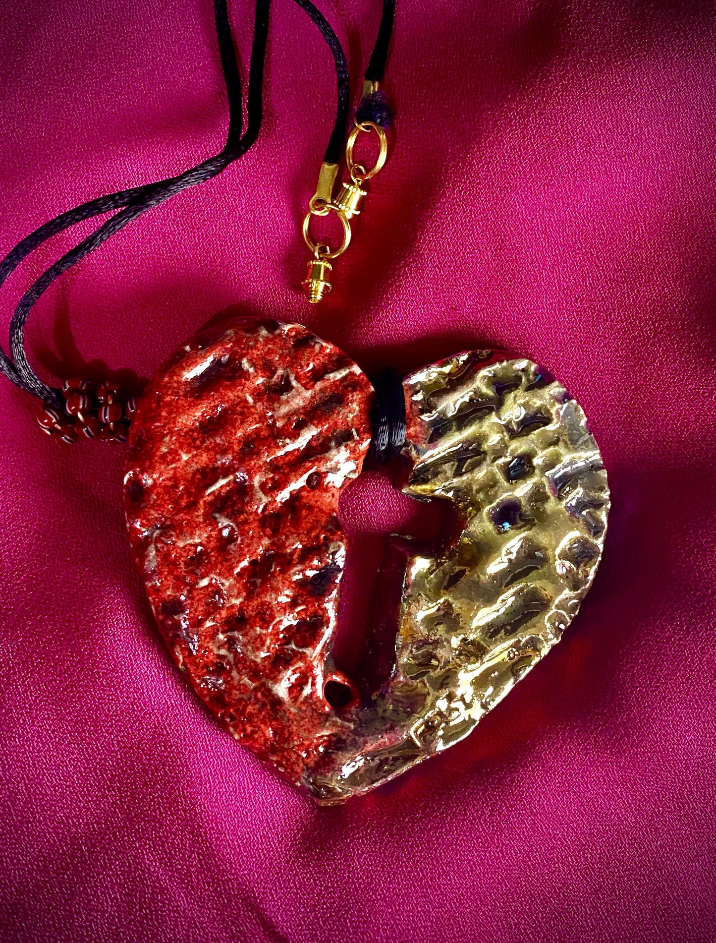 Have A Heart ! Each heart pendant is handmade with love! It is 3"x 3" and weighs approx. 3ozs. This pendant has a  ruby red and gold metallic raku glazes that renders a unique translucent  patina. The heart  has a textured  pattern with a cut out cross in the center.. It holds a spiral of ruby red mini beads on a spiral copper wire. This pendant has a nice 12" black suede cord!