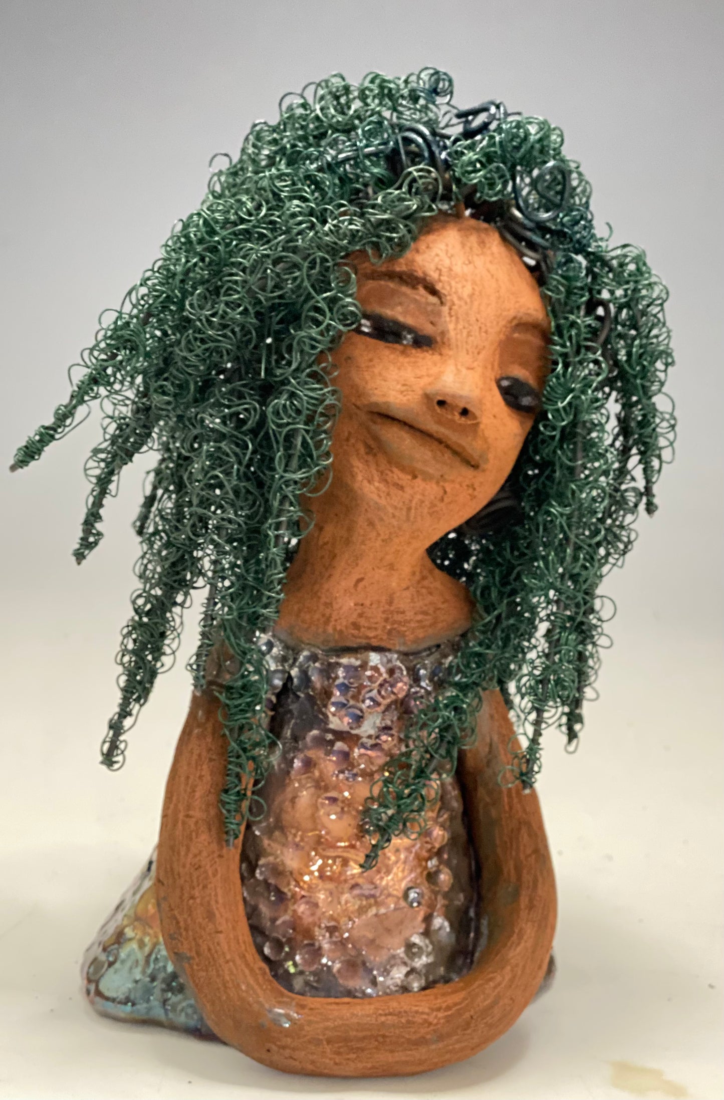 Nia Nia stands 8" x 5" x 5.5" and weighs 1.04 lbs. She has a lovely honey brown complexion with soft brown lips. She has long twisted wire locs hairstyle waist down!  Nia has a glossy metallic copper glazed dress. She has over 75 feet of 16 and 24 gauge emerald green wire for hair. It really took over 6 hours just to twist and do her hair! With  eyes wide opened, Alexis has hope of finding a new home.   