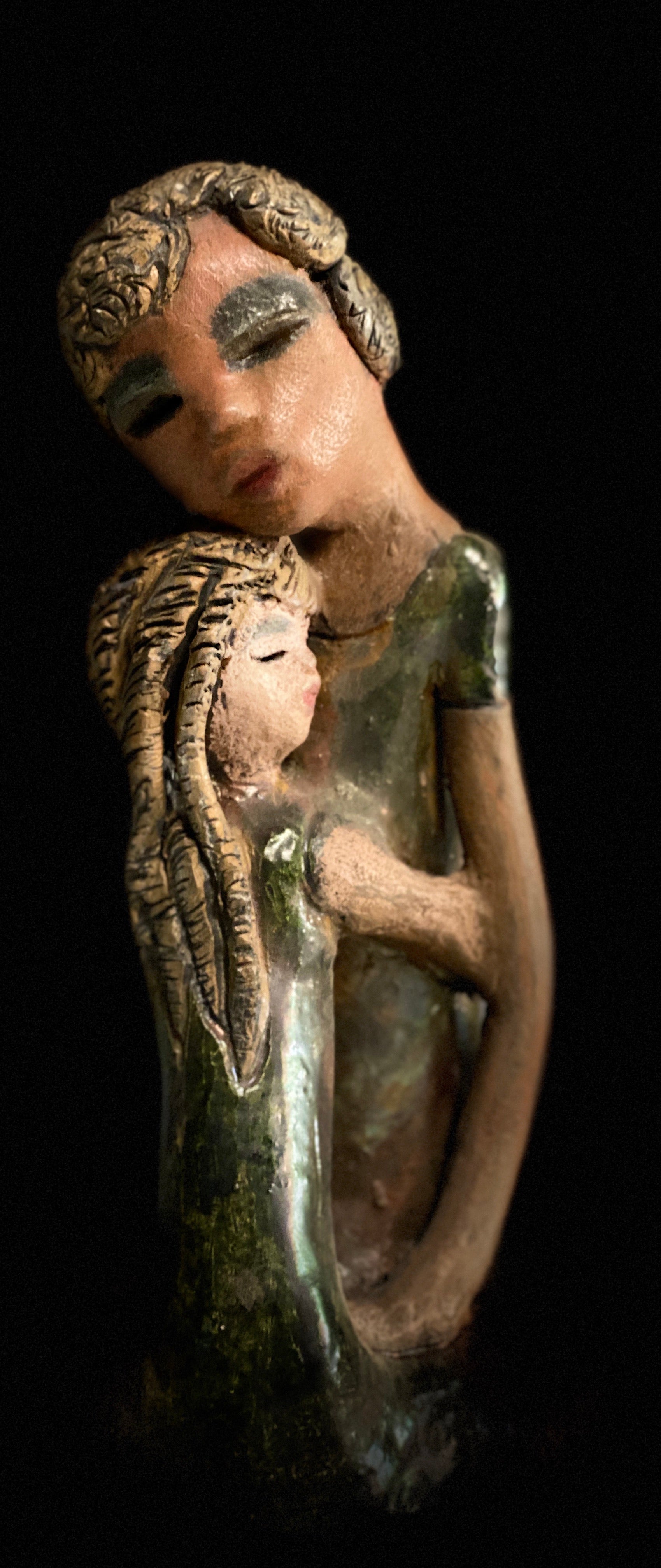 "Hold Me Mama has a very similar look and feel as                             Girl Talk with my Mom". Hold Me Mama depicts the bond between a mother and child". They stand 10" x 5" x 5" and weighs 2.8 lbs. Mother and Child has honey brown complexions  with etched copper colored  clay hair. They wear green/ copper raku fired glossy dresses.  Mother assures her daughter  that everything will be alright!