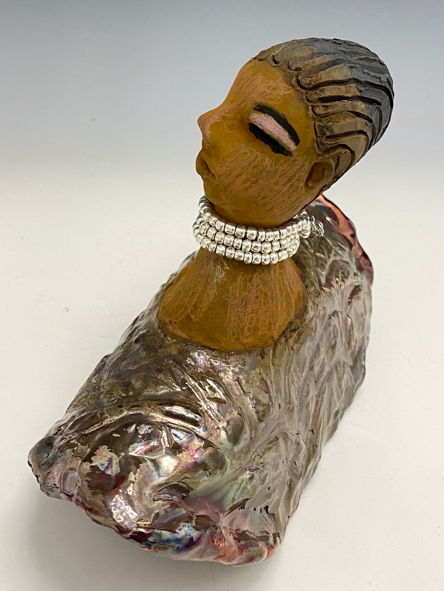 Belinda looks up with joy and anticipation! Belinda stands 6" x 8" x 4" and weighs 1.40 lbs. She has a beautiful textured copper robe trim. Belinda has braided clay hair. She has a honey brown complexion and soft light brown lips. Belinda will make for great conversation in your home.