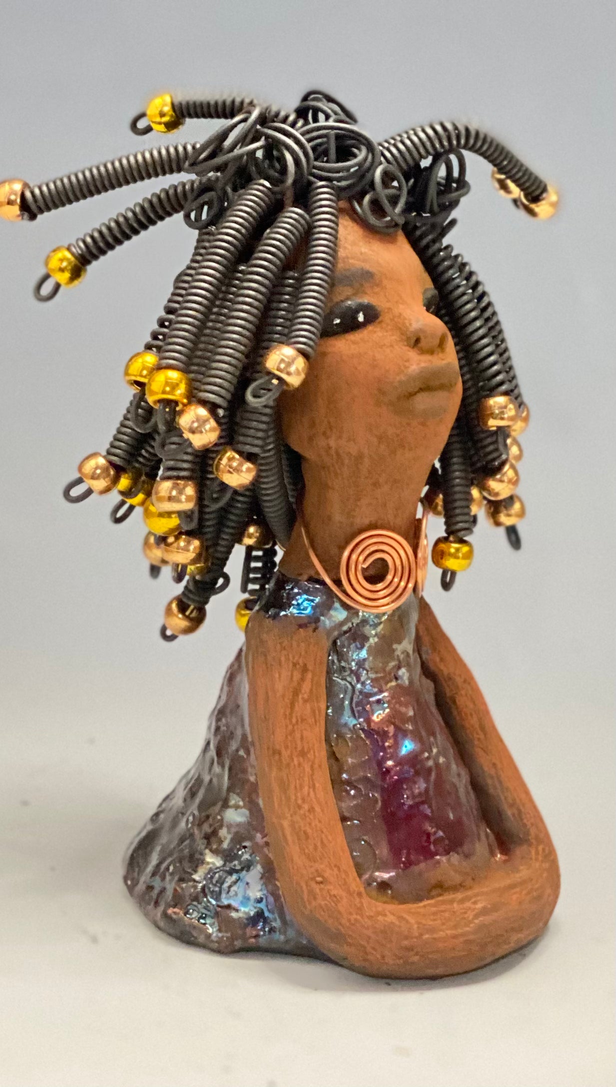   Meet Alexus  Alexus stands 7.5" x 4" x 4" and weighs 1.05 lbs. She wears a lovely glossy  metallic gold dress adorn by a spiral copper necklace. Alexus has over15 feet of coiled wire hair with gold beads.. Alexus appears to sit in a yoga pose. Her long arms rest at her side. Alexus is a great starter piece from the Herdew Collection!