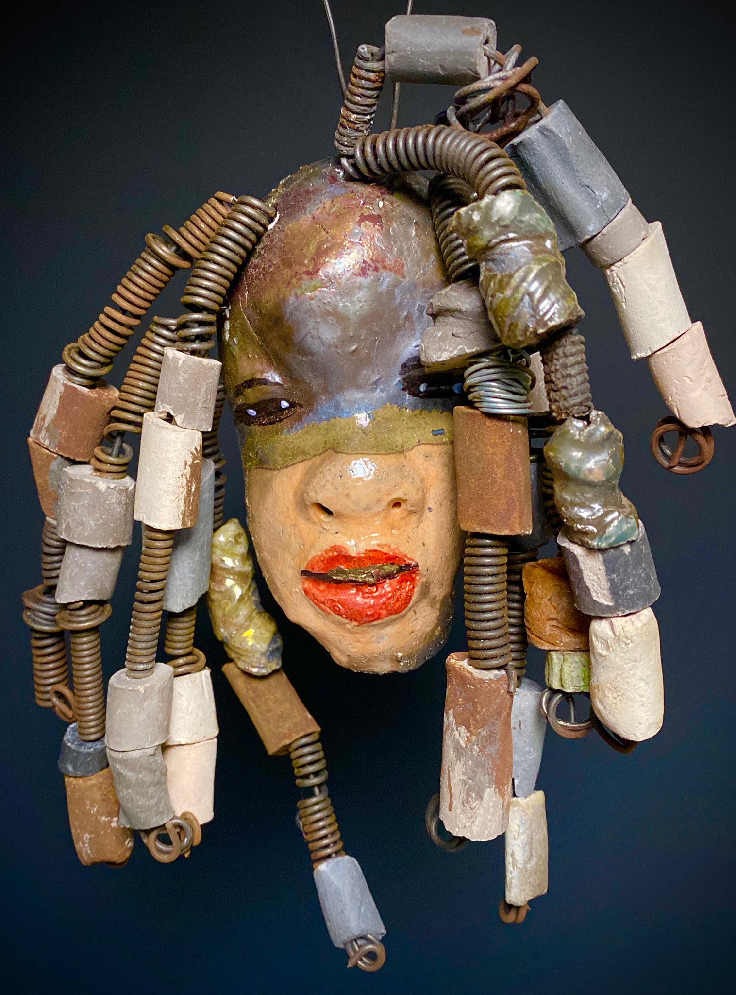 I started making art soon after seeing authentic African artwork at the Smithsonian Museum of African Art. I was in total awe. Kenna was inspired by my visit there.   Kenna has a two tone  light and dark honey metallic complexion. Her hair can be adjusted up to  11" x 10" and weighs 1. lbs Kenna has  over 20 handmade multicolored raku fired beads. She has over 20 feet of coiled 16 gauge wire hair. Kenna is ready for display!