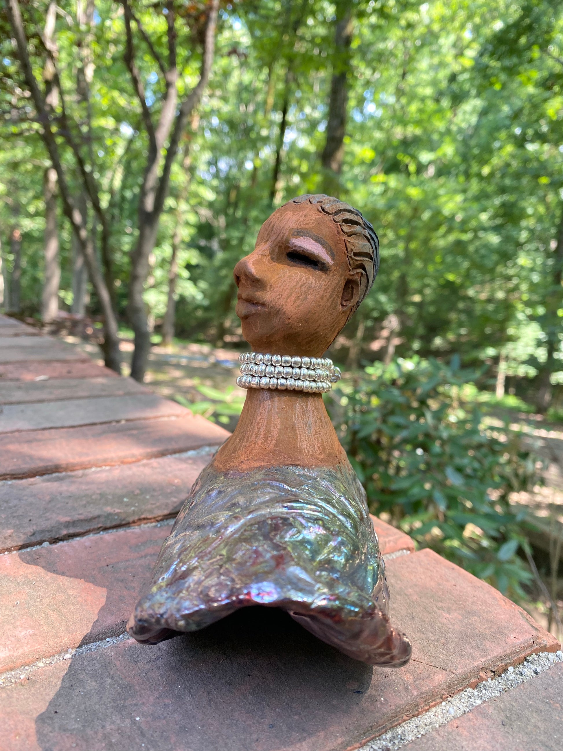 Belinda looks up with joy and anticipation! Belinda stands 6" x 8" x 4" and weighs 1.40 lbs. She has a beautiful textured copper robe trim. Belinda has braided clay hair. She has a honey brown complexion and soft light brown lips. Belinda will make for great conversation in your home.