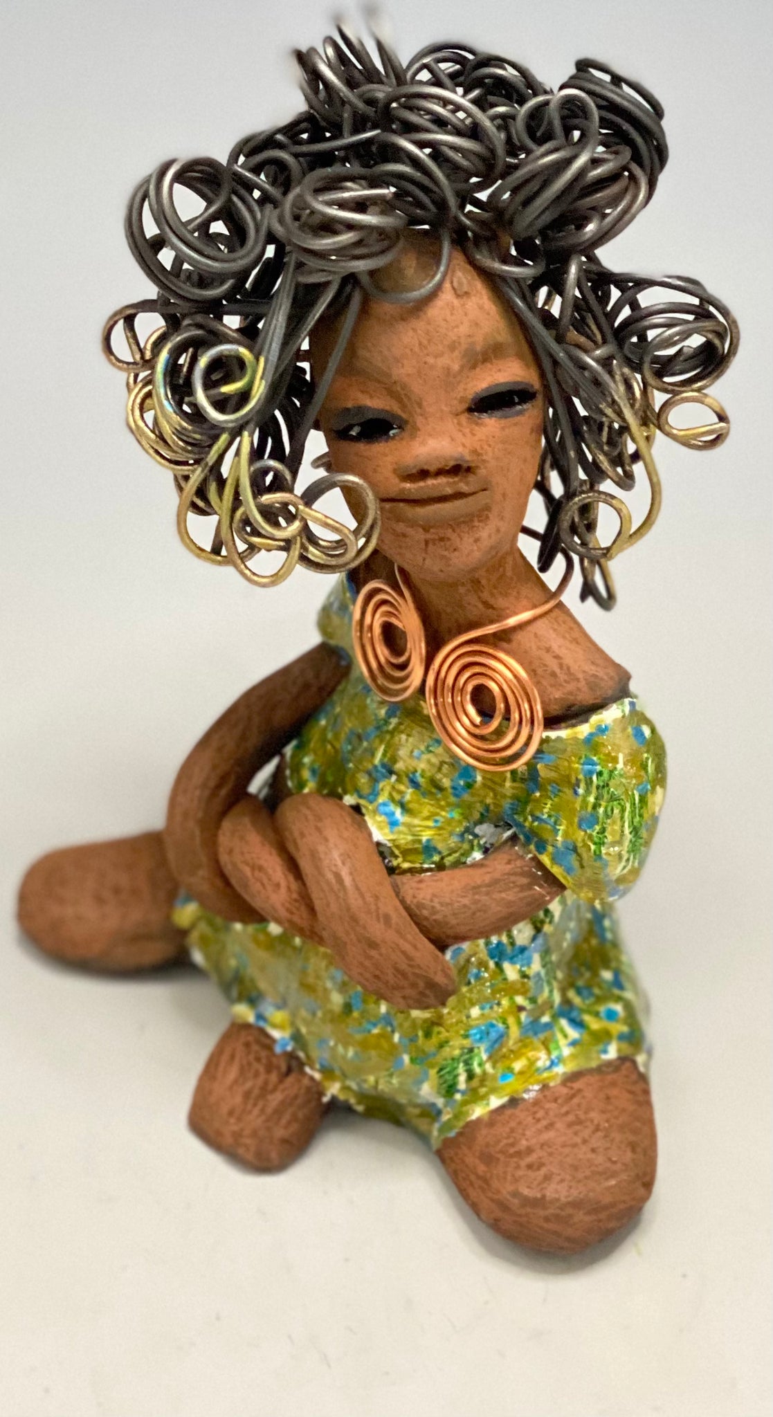 Jayla stands 7" x 5" x 4.5" and weighs 14 ozs. She has a lovely honey brown complexion with cocoa brown lips. She has a big hairstyle!  Brianna has a colorful  blue green antique glazed dress. She has over 15 feet of 16 gauge wire for hair. It took over 2hours just to do her hair! With  eyes wide opened, Jayla has hope of finding a new home.     You will love having Jayla! She will attract and spark conversation with guest in your home!