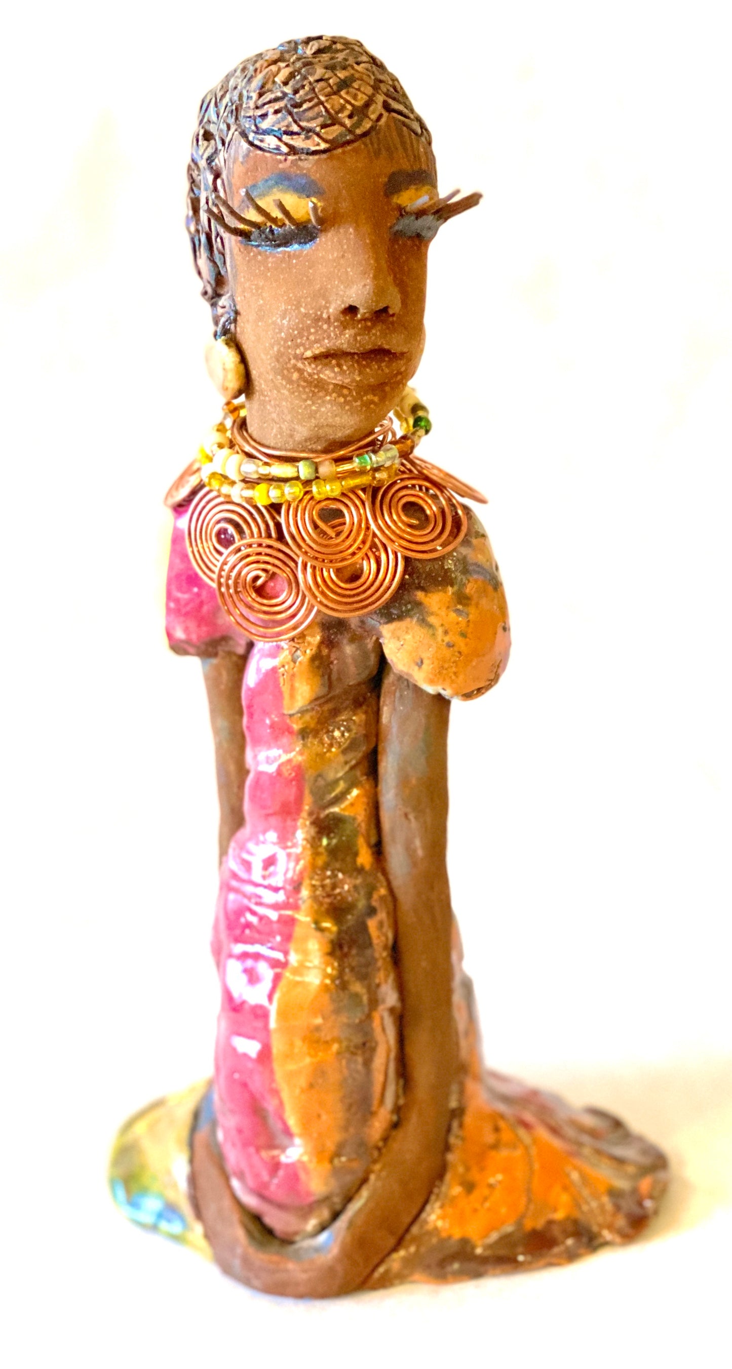 Keeba  long loving arms rest beside her multicolored metallic dress. She wears a spiral copper necklace. Keeba  is a sophisticated lady that will grace your home.