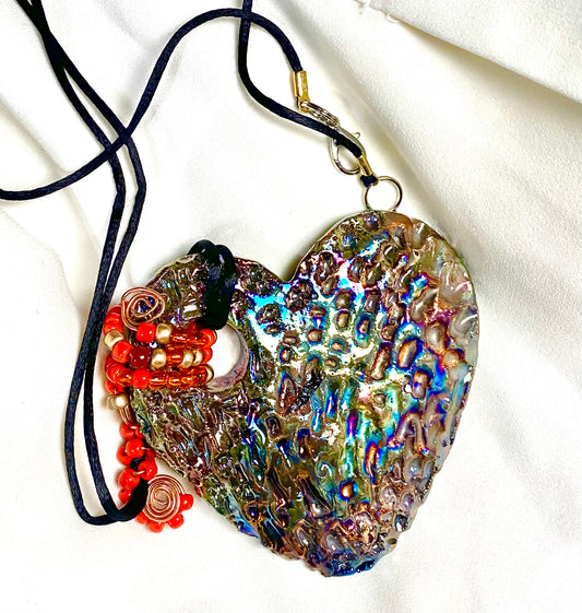 Have A Heart ! Each heart pendant is handmade with love! It is 3"x 3" and weighs approx. 3ozs. This pendant has a copper gold metallic raku glazes that renders a unique translucent  patina. The heart has a textured pattern . It holds a spiral of amber and red mini beads on a spiral copper wire. This pendant has a nice 12" black suede cord!