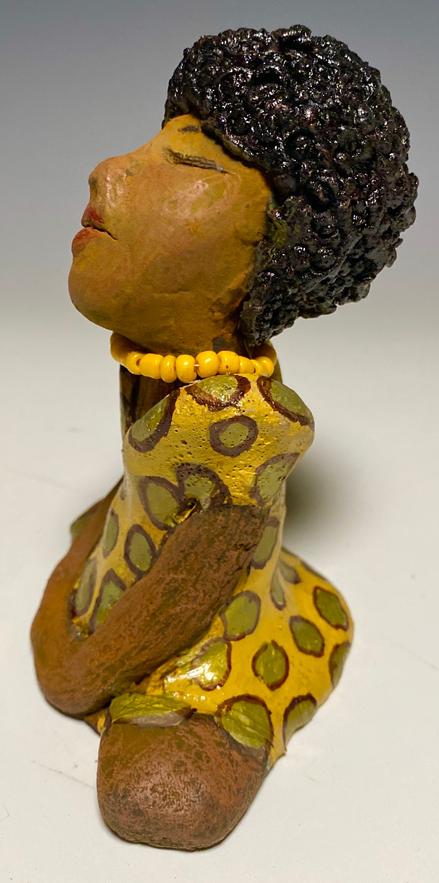 Meet Shelia! Shelia stands" 5 x 4" x 3" and weighs 11 ozs. She wears a cute spotted autumn yellow dress with matching beads. She has a lovely honey brown complexion with an awesome black afro.. Her long loving arms rest at her side. With the current situation we All are going through, Shelia will place a smile on your face during this challenging time. 