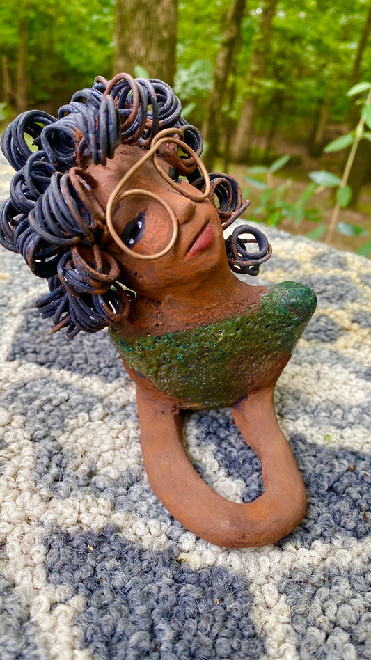 Meet Elma the Mermaid !﻿ Elma stands 6" x 8" x 4" and weighs 1.07 lbs. Elma has a lovely honey brown complexion. Elma's body has a copper green metallic glaze She has over 25 feet of curly wire hair. Elma looks up in anticipation of being a part of your home!