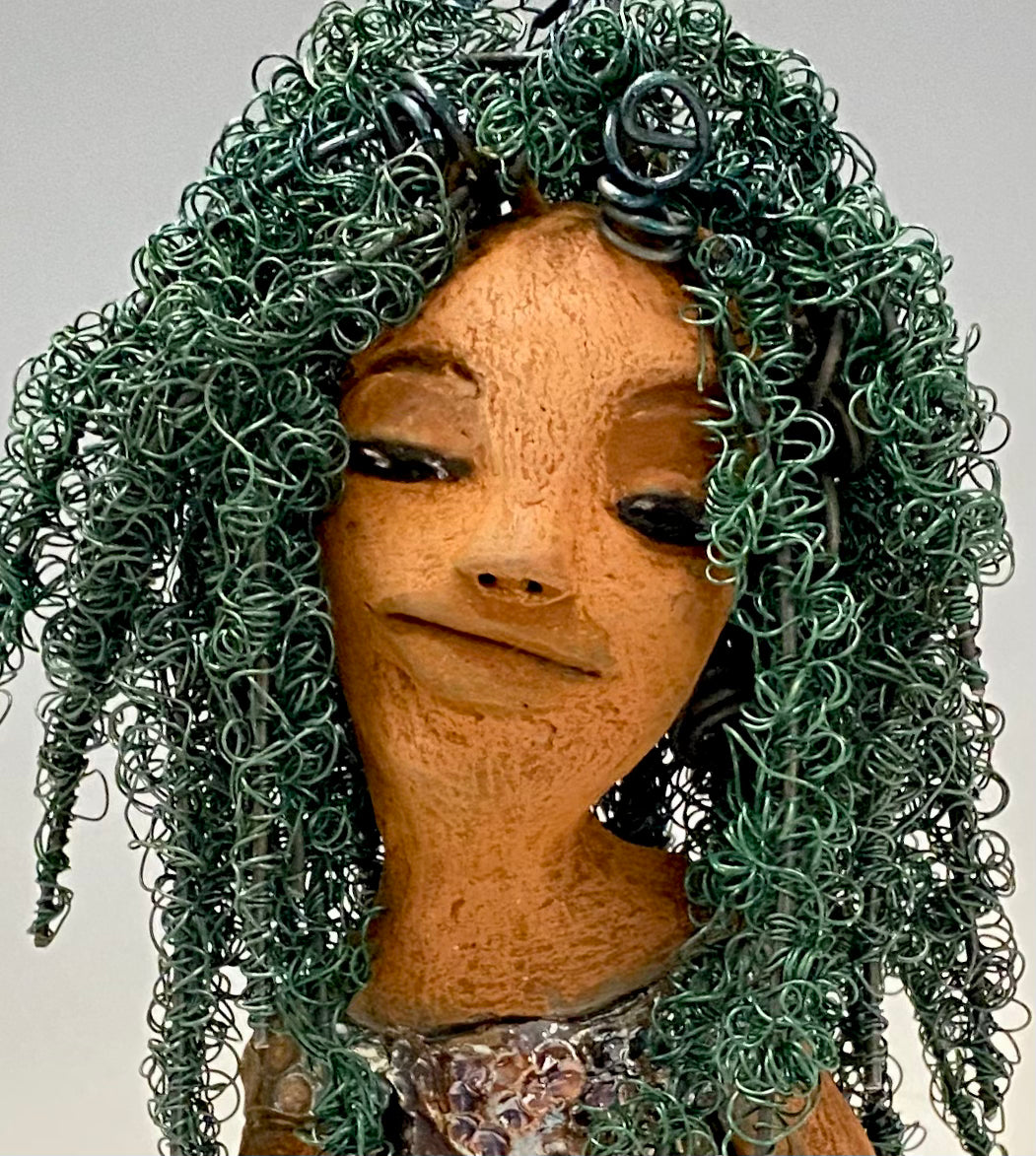 Nia Nia stands 8" x 5" x 5.5" and weighs 1.04 lbs. She has a lovely honey brown complexion with soft brown lips. She has long twisted wire locs hairstyle waist down!  Nia has a glossy metallic copper glazed dress. She has over 75 feet of 16 and 24 gauge emerald green wire for hair. It really took over 6 hours just to twist and do her hair! With  eyes wide opened, Alexis has hope of finding a new home.   