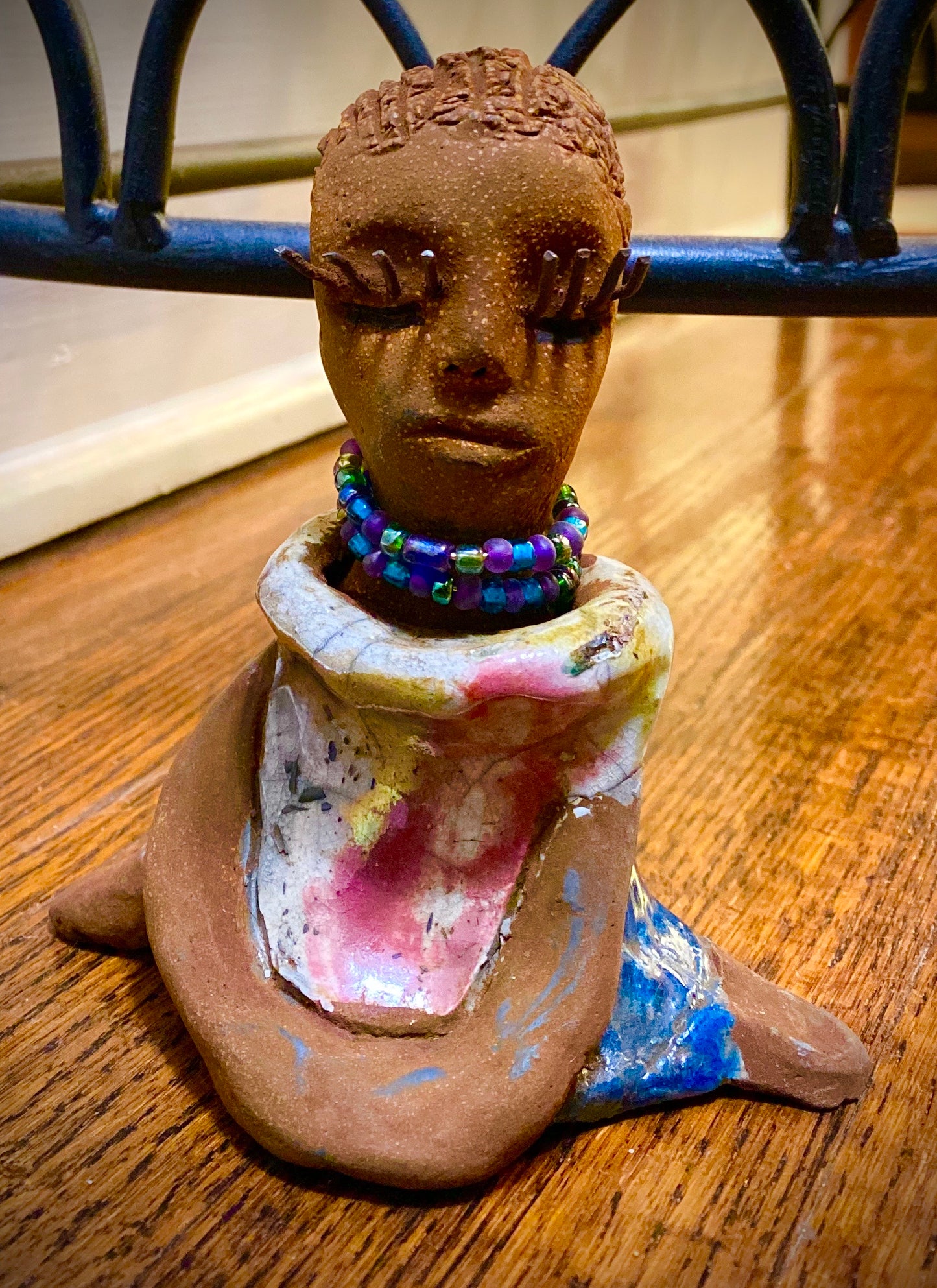 Riley stands 5" x 5”x 3" and weighs  11 ozs.  Riley has a lovely multicolored glossy dress with a matching beaded necklace.  She has long lashes!  Riley appears to sit in a yoga pose. Her long arms rest at her side.