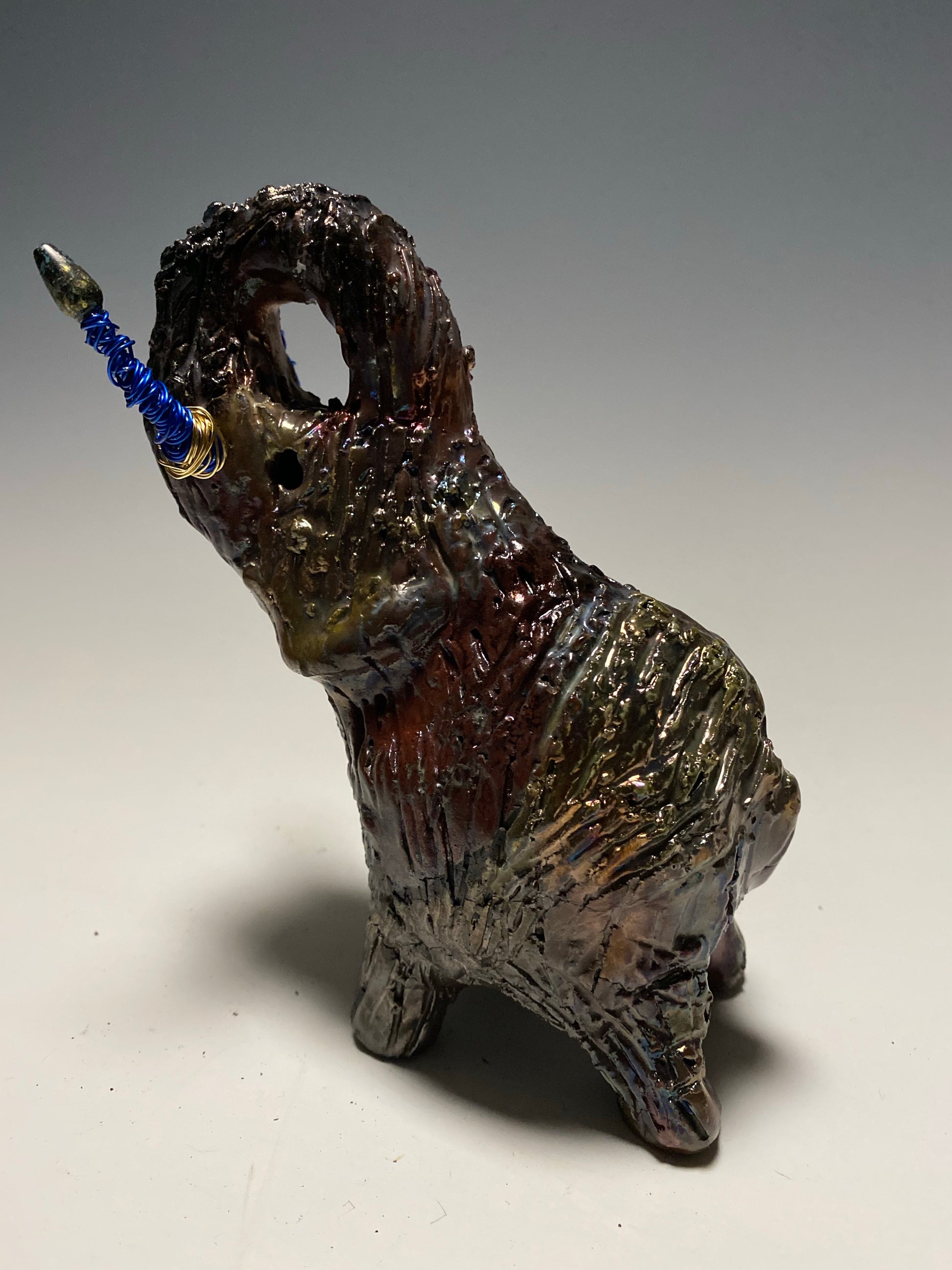 Raku Elephant Have you HERD!!!!!!  Just one of these lovely Raku Fired Elephant will make an excellent gift for your  friend, sorority or for your home’ special place centerpiece.   6" x 4" x 4" 1 lbs Beaded tusk with blue and gold wire Beautiful  colorful metallic raku elephant For decorative purposely only