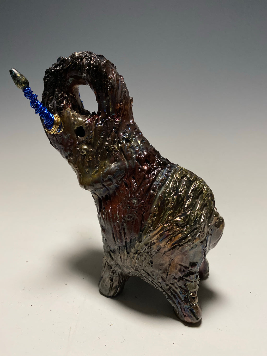 Raku Elephant Have you HERD!!!!!!  Just one of these lovely Raku Fired Elephant will make an excellent gift for your  friend, sorority or for your home’ special place centerpiece.   6" x 4" x 4" 1 lbs Beaded tusk with blue and gold wire Beautiful  colorful metallic raku elephant For decorative purposely only