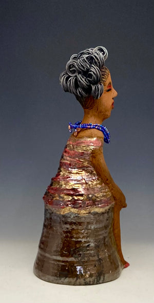 You know someone like Kim. One who reaps elegance and sophistication!  Kim stands 13" x 5" x 7" and weighs 2.07 lbs.  She has a lovely light beige complexion with over 4 feet of 16 gauge spiral coiled wire hair.  Kim's metallic copper red and gold dress is accented by a multicolored aqua blue beaded necklace. Kim's  maroon eye shadow gives her a distinguished mystical look. One must  wonder what is Kim thinking? Kim sits with her legs crossed as she awaits a special place to grace your home.