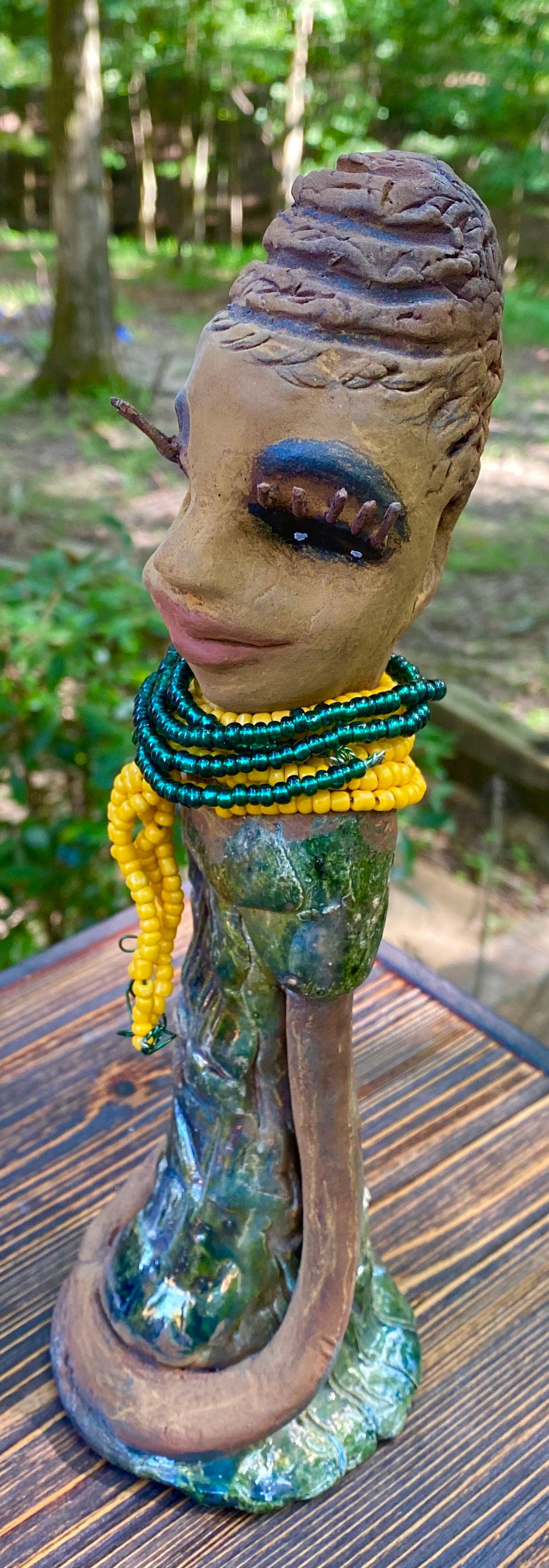 Meet Jazmyne! Jazmyne stands 11" x 4" x 4" and weighs 2.5 lbs. She has a lovely honey brown complexion with  reddish brown lips. She has a braided hairstyle.  Jazmyne has a colorful metallic green antique copper glazed dress. She wears a bright yellow beaded necklace. With long lashes and eyes wide opened, Jazmyne has hopes of finding a new home.    Jazmyne  will attract and spark conversation with guest in your home!