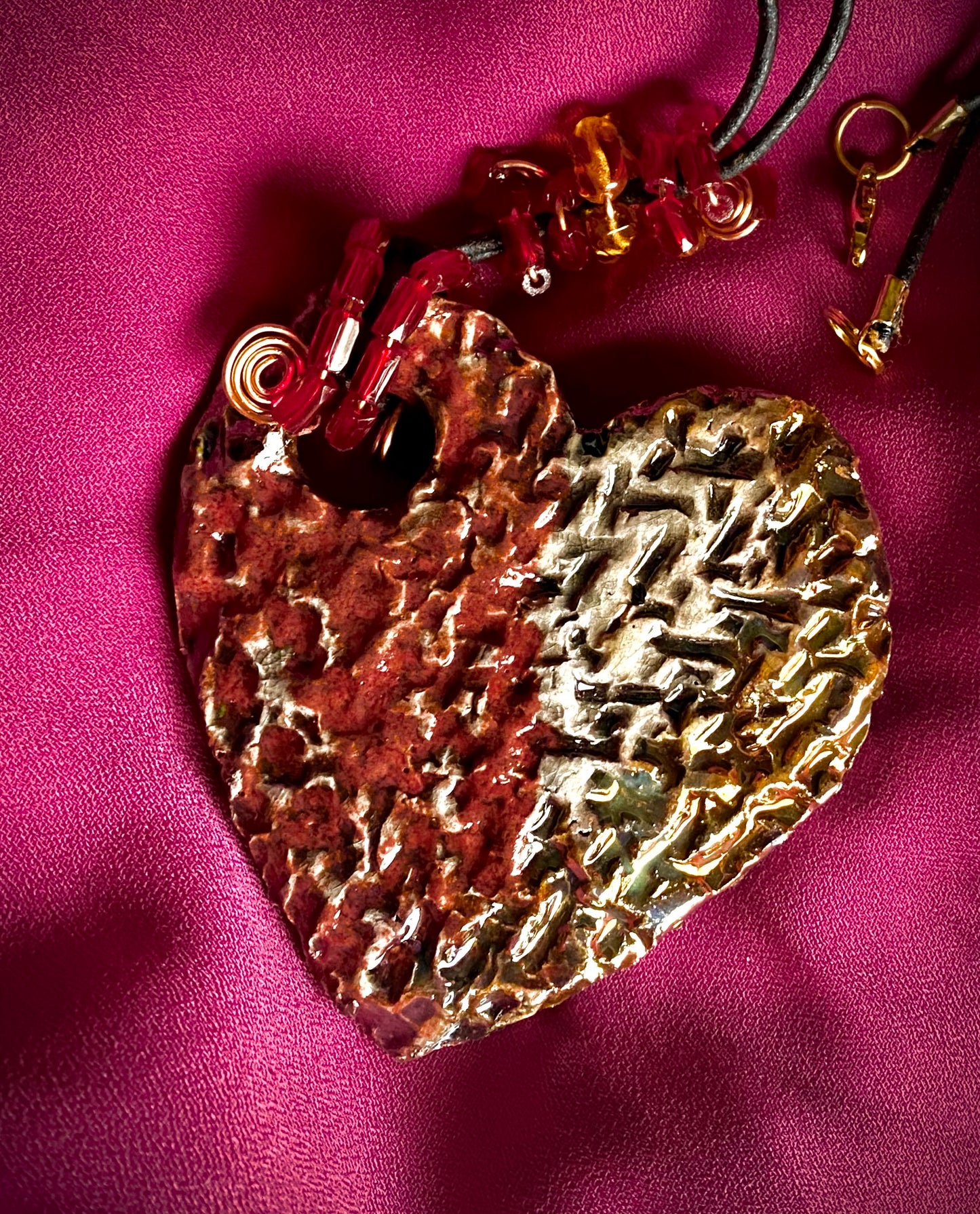 Have A Heart ! Each heart pendant is handmade with love! It is 3"x 3" and weighs approx. 3ozs. This pendant has a  ruby red and off white metallic raku glazes that renders a unique translucent  patina. The heart  has a textured  pattern. It holds a spiral of ruby red mini beads on a spiral copper wire. This pendant has a nice 12" black suede cord!