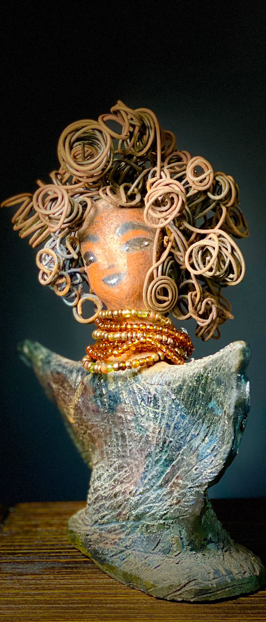 Lizzie Got Big Hair! Lizzie stands 8" x 7" x  2.5" and weighs 1 lb. Her robe is textured with a multicolored metallic copper glaze. Lizzie has really Big Hair. The hair is over 25 feet of curly 16 gauge wire. Her complexion is a lovely cocoa brown. Lizzie has an angelic pose with her arms up in adoration. Give Lizzie a specail place in your home!