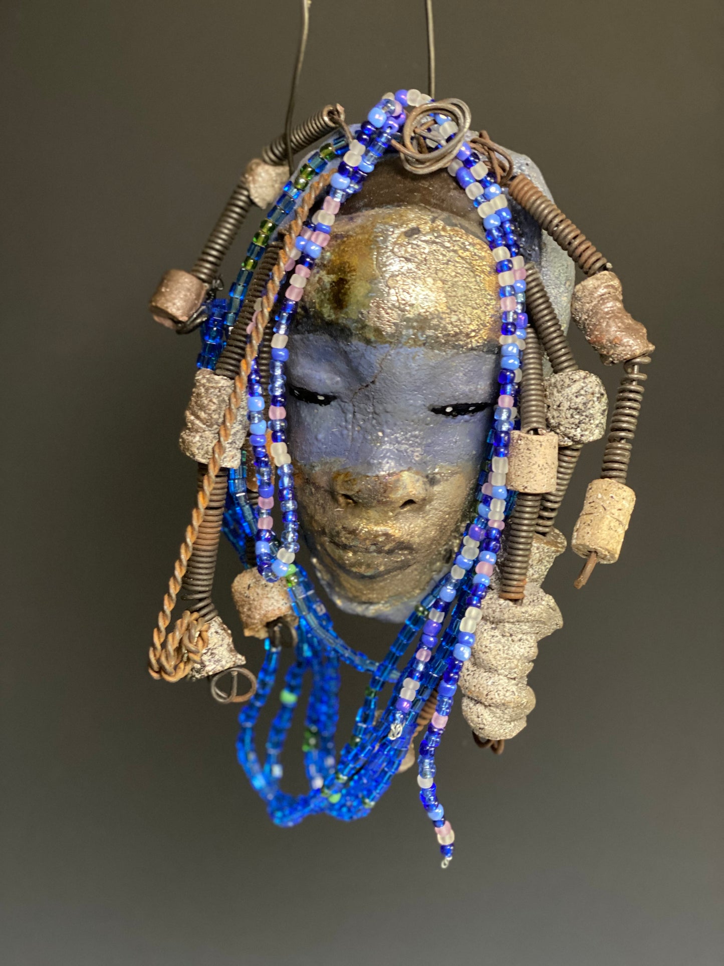  Meet Randi! I started making art soon after seeing authentic African artwork at the Smithsonian Museum of African Art. I was in total awe. Randi was inspired by my visit there.   Randi has a two tone complexion of golden silver and blue. She is 8" x 6" and weighs 14 ozs. Randi has over 10 raku beads. She has over 200 of multi shade of blue and white mini beads. Randi has over 10 feet of  coiled copper and 16 gauge wire hair.