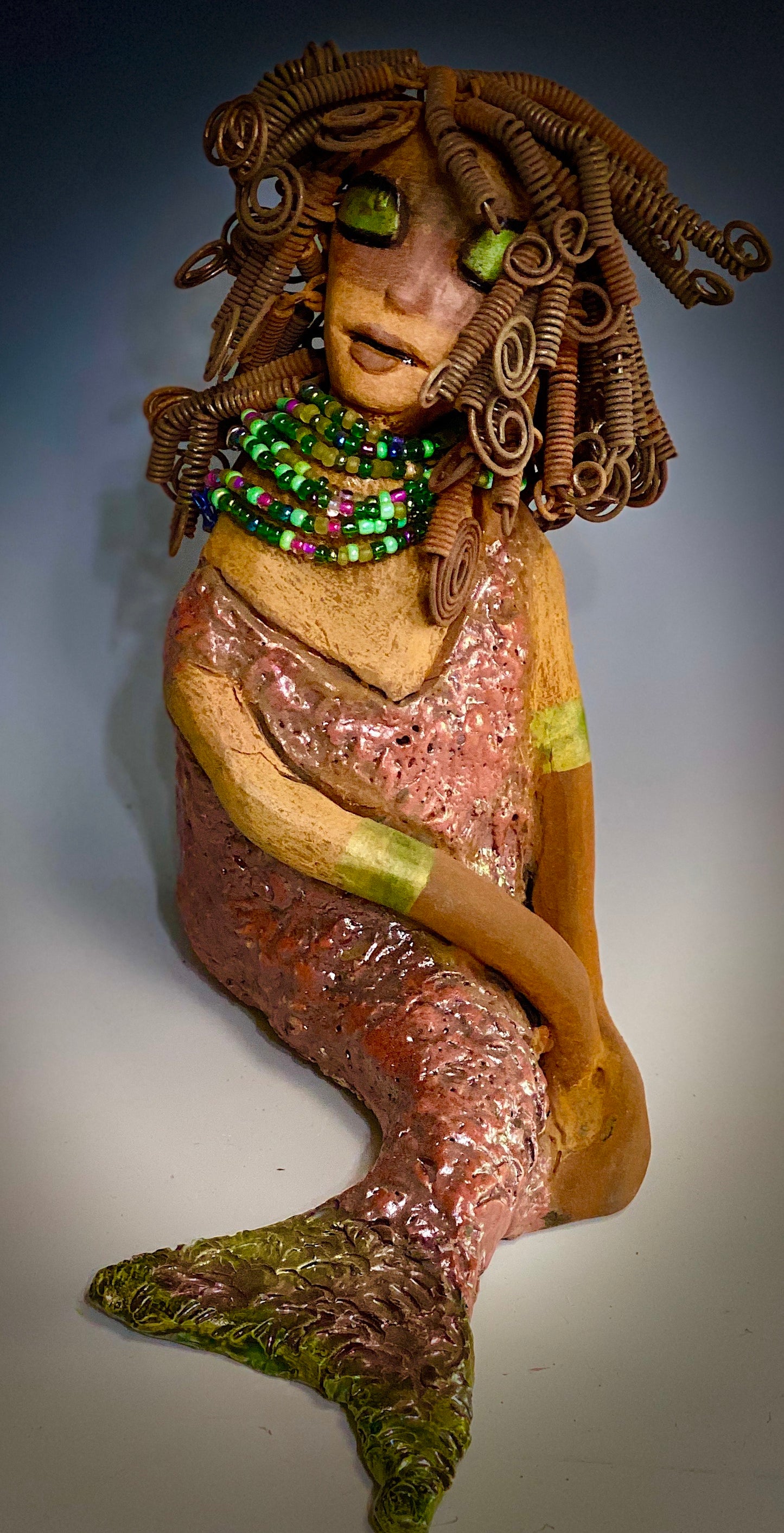 "Honestly, I can not explain where this desire to make mermaids come from. When I created my first raku fired mermaid, I was amazed at how well my homemade metallic copper green glaze worked with the mermaid's body suit. It was a good match with the honey brown complexion I use with most of my sculptures".  Compare Meranda with Melody the mermaid.