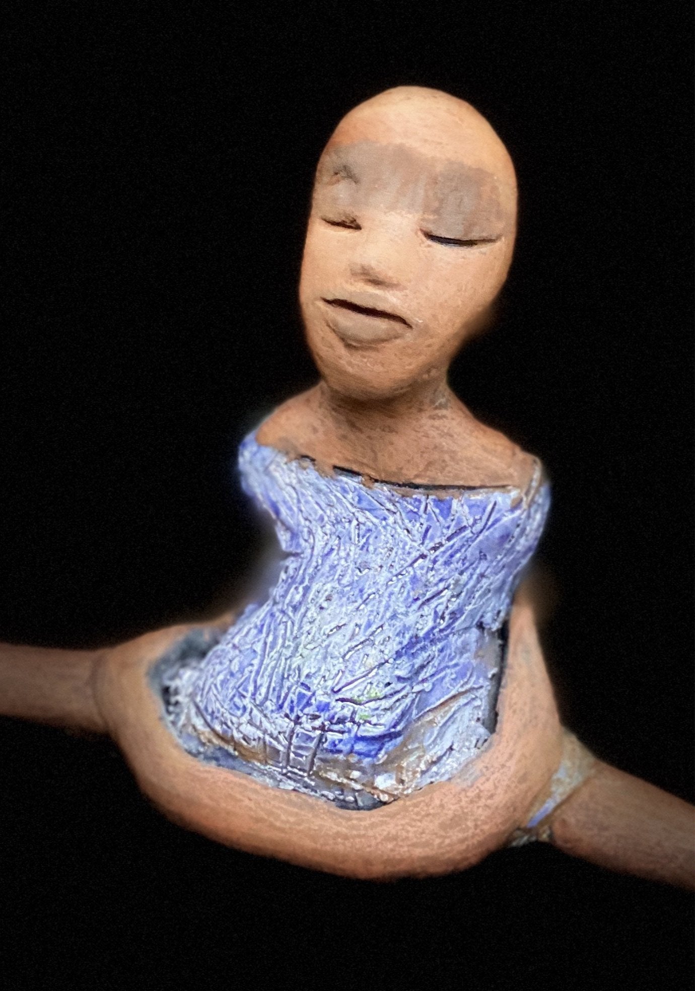 "Vida sits with her mind on peace and meditation". Vida sits 5" x 6" x 3" and weighs 10 ozs. She is in a comfortable yoga pose. Vida has a lovely two tone honey brown complexion.  She is without hair! Vida has a textured light blue with matching blue shoes.