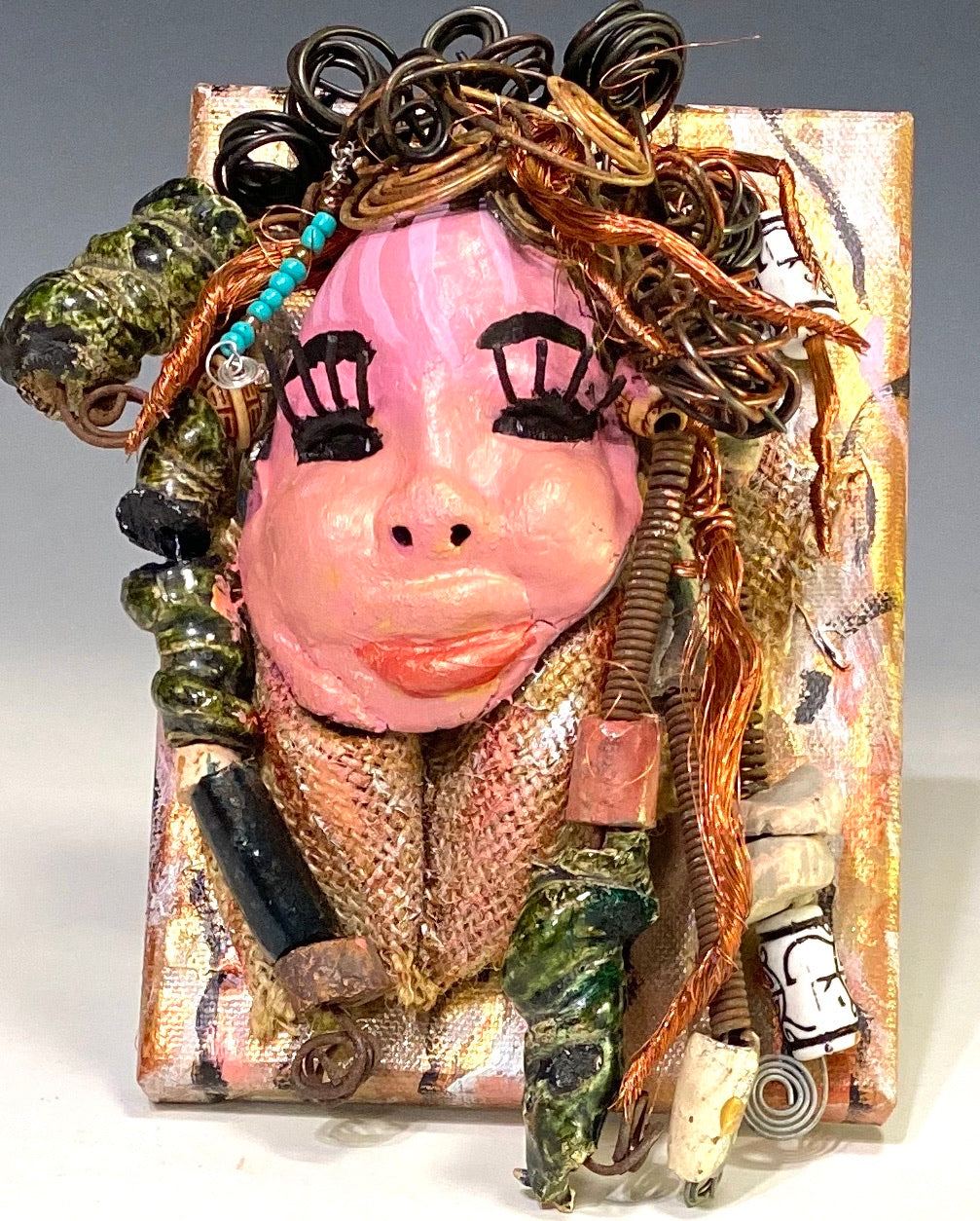 Peggy has a pink and white complexion with ruby red lips! She is mounted on a  5” x 7” and weighs 1.2 lbs. Peggy  has an awesome blue tribal beaded hair dress. She has over 30 feet of coiled 16 gauge wire and copper strands of hair.