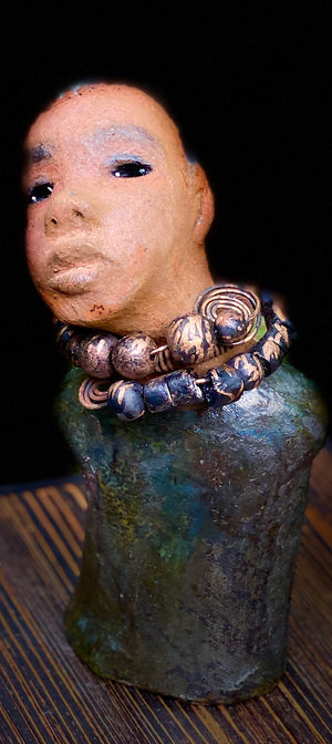 "It is obvious Herdew implies that most of my sculptures are female. My goal this year is to create ten male sculptures. Alvin is one of the first that I am pleased with. Alvin stands 9" x 4" x 4" and weighs 2.13 lbs. He wears a metallic multi colored jacket with metallic beads. Alvin has a dark honey brown complexion. Alvin seems to be in deep thought. Alvin  would display proudly in your home.