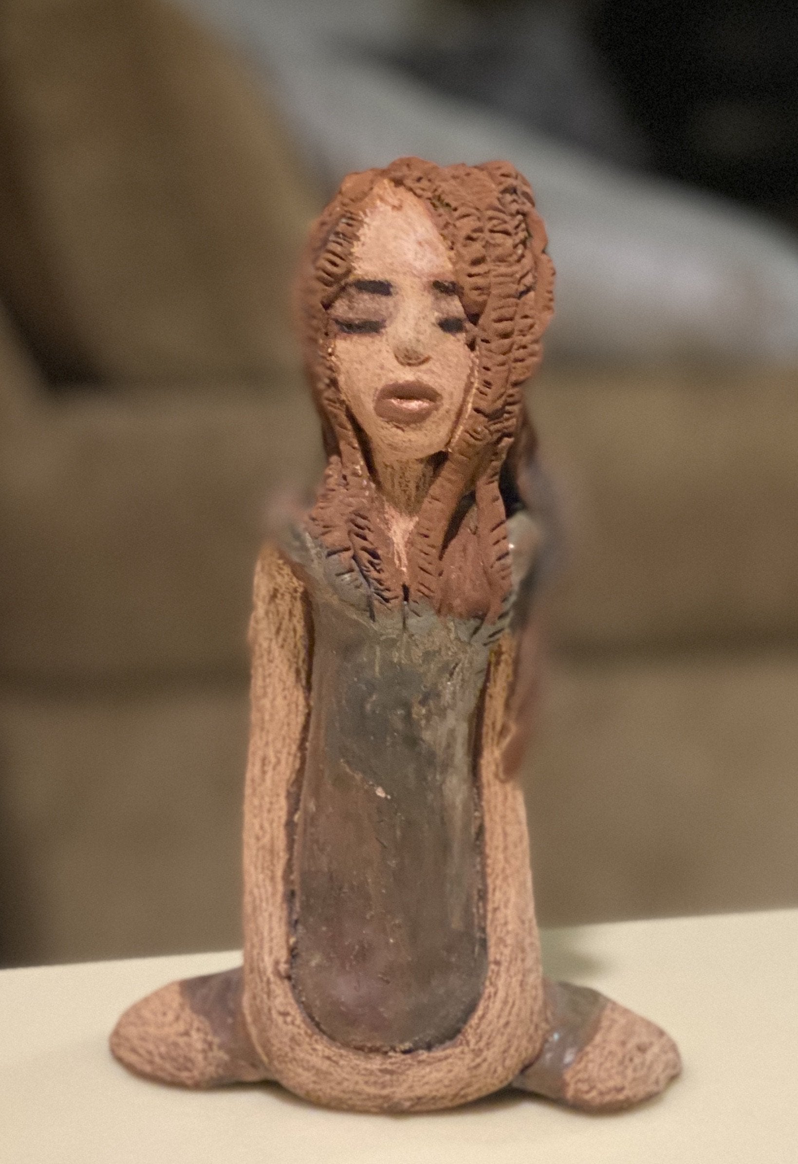 Amani stands 8" x 5" x 2.5" and weighs 1.03 lbs. She has a lovely beige brown complexion with long etched braided clay hair.   Amani long loving arms rest beside her copper green dress. Amani is a sophisticated lady that will grace your home.