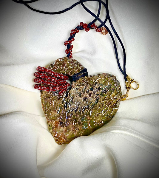  Have A Heart ! Each heart pendant is handmade with love! It is 3"x 3" and weighs approx. 3ozs. This pendant has a white and gold metallic raku glazes that renders a unique translucent  patina. The heart has a textured with cut out cross pattern . It holds a spiral of multicolored mini beads on a spiral copper wire. This pendant has a nice 12" black suede cord!