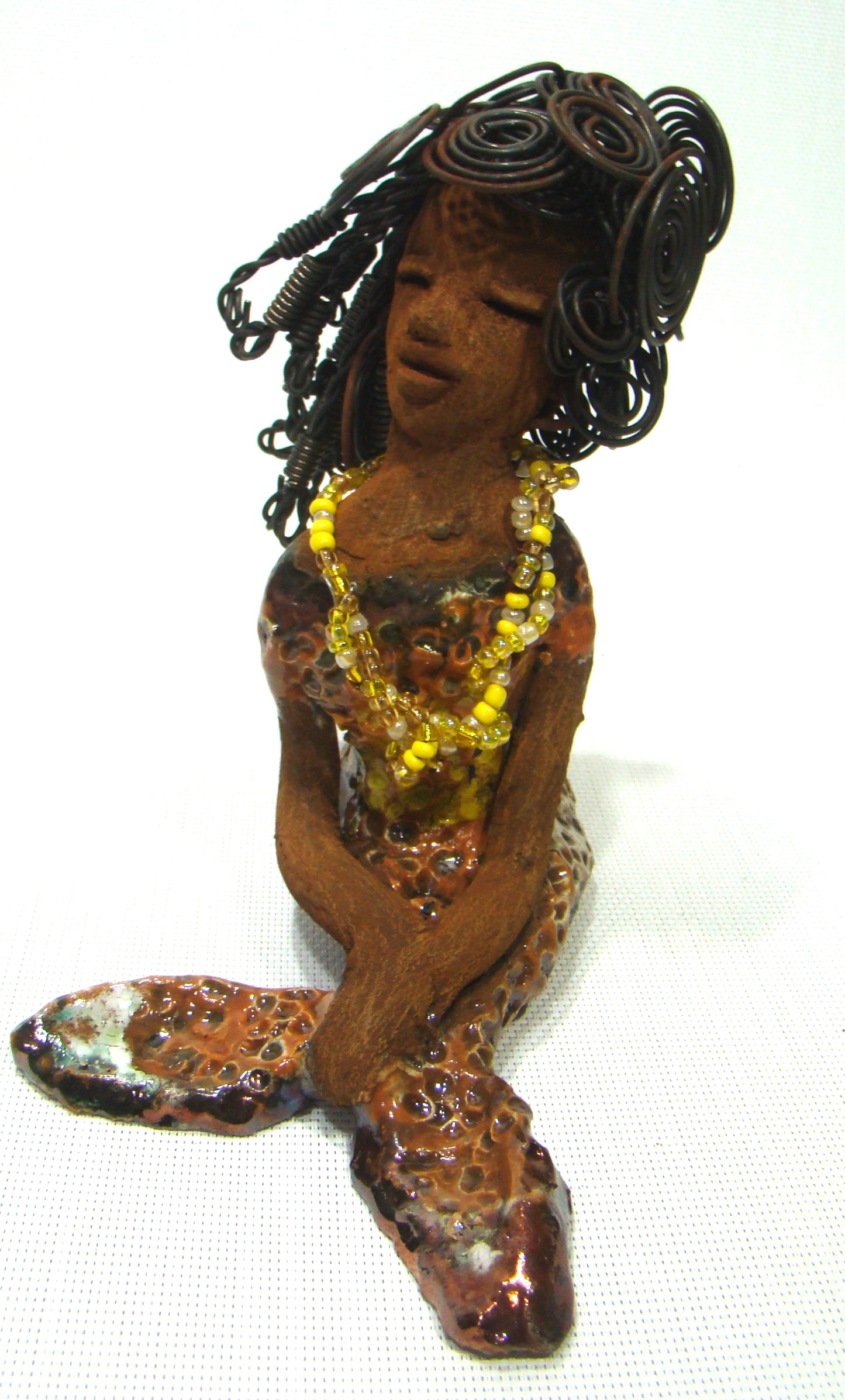 Meet Isabella the Mermaid!          Isabella stands 7' x 4" x 6" and weighs 1.08 lbs..         Isabella  has a lovely brown complexion.         Her long loving arms are crossed in her lap.         Isabella has over 20 feet of  wire hair.         It took over two hours to fix her hair!         Isabella has a metallic yellow swimsuit with flashes of copper.         She wears a yellow beaded necklace.  Isabella appears to have something on her mind!