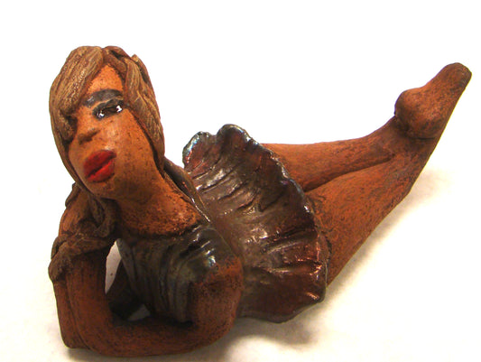      Juanita  stands 4" x 3" x 7" and weighs 1 lb.     She has a lovely honey brown complexion.     Juanita has a copper iridescent  dress.     Her long loving arms rest underneath her face as she  caresses her brown clay hair.     Juanita will definitely get your guest attention and create conversation.